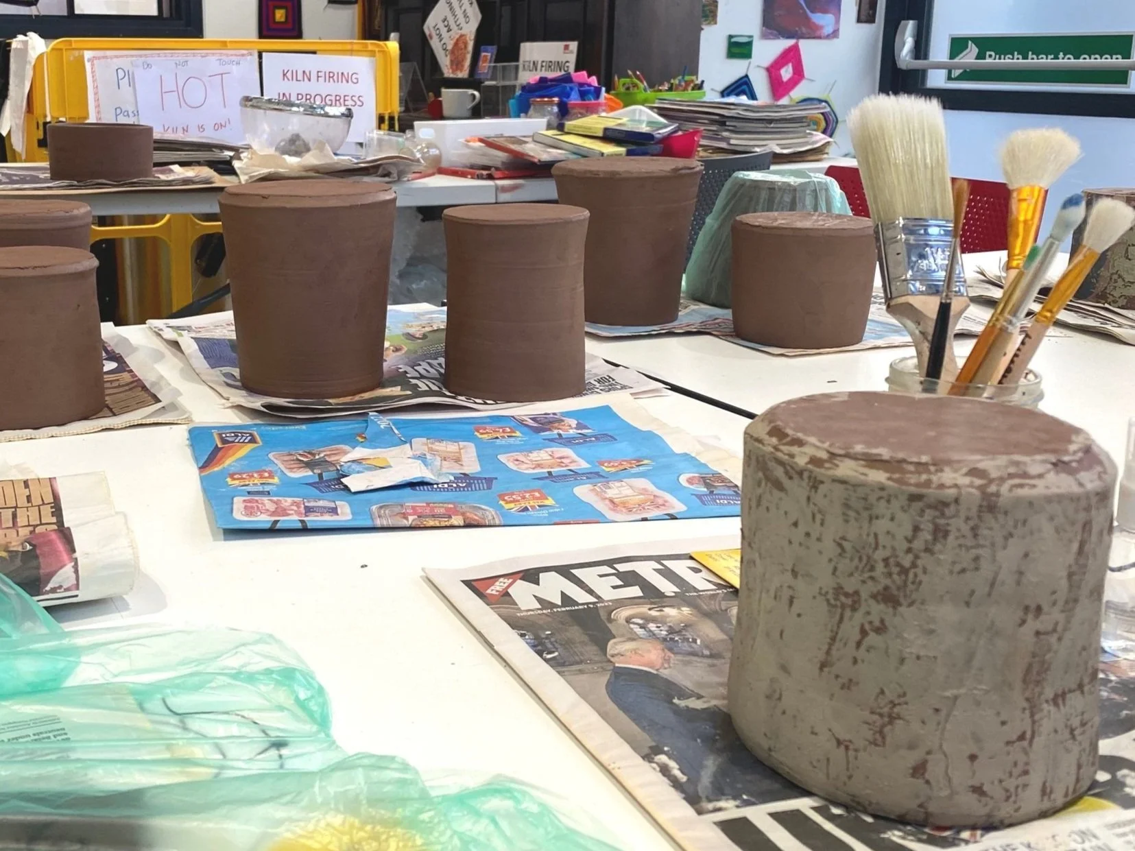 Large studio space. Image of thrown terracotta vessels positioned on the table up side down