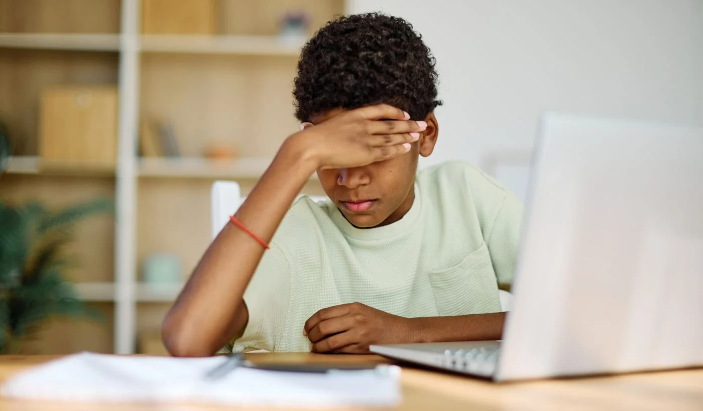 An Afro_american boy falling asleep  while learning at the laptop due to narcolepsy