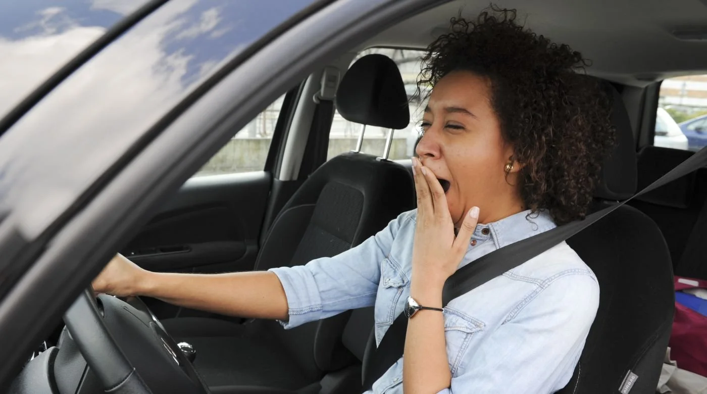 Fatigues yawning Afro-American woman driving a car