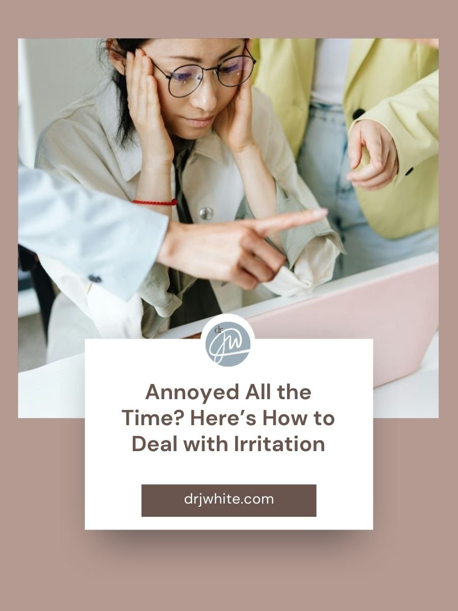 Blog Post Cover for Annoyed All the Time? Here’s How to Deal with Irritation. Woman sits at computer with coworkers pointing to her laptop critiquing her work. Using defusion can help you take a moment to recenter and respond intentionally