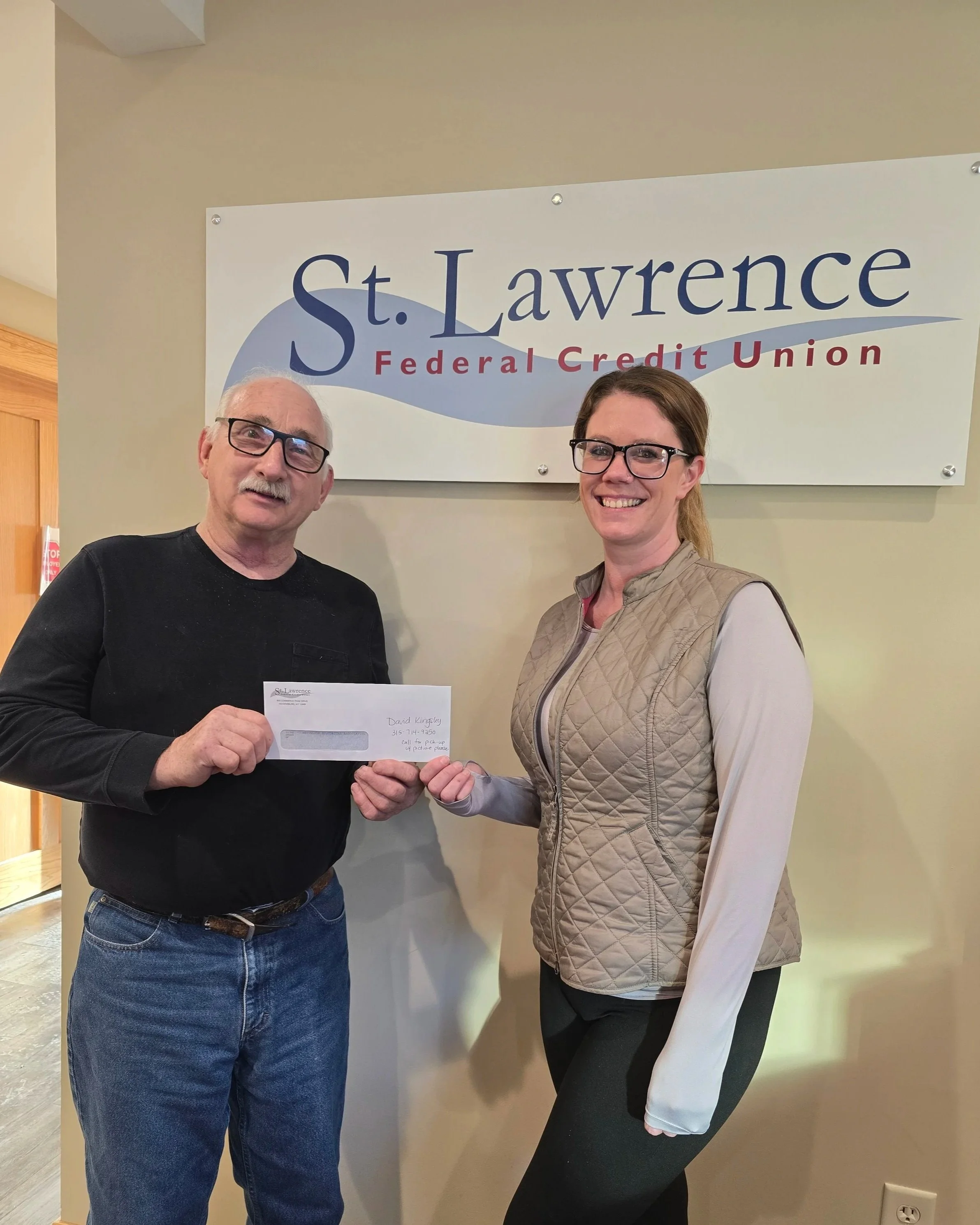 One adult female presenting a donation check to one adult male for te Heuvelton Historical Association.