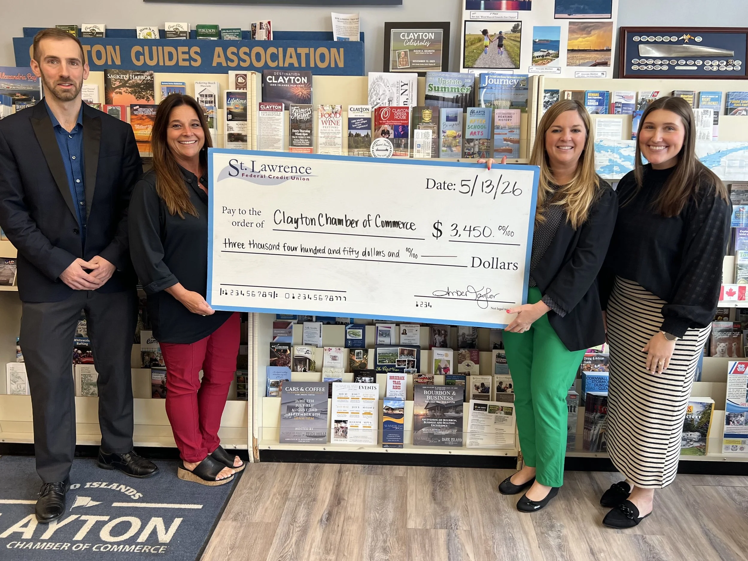 One adult male and two adult females are presenting a large in size check to a aduly female with the clayton chamber of commerce to benefit and sponsor some of their 2026 events.