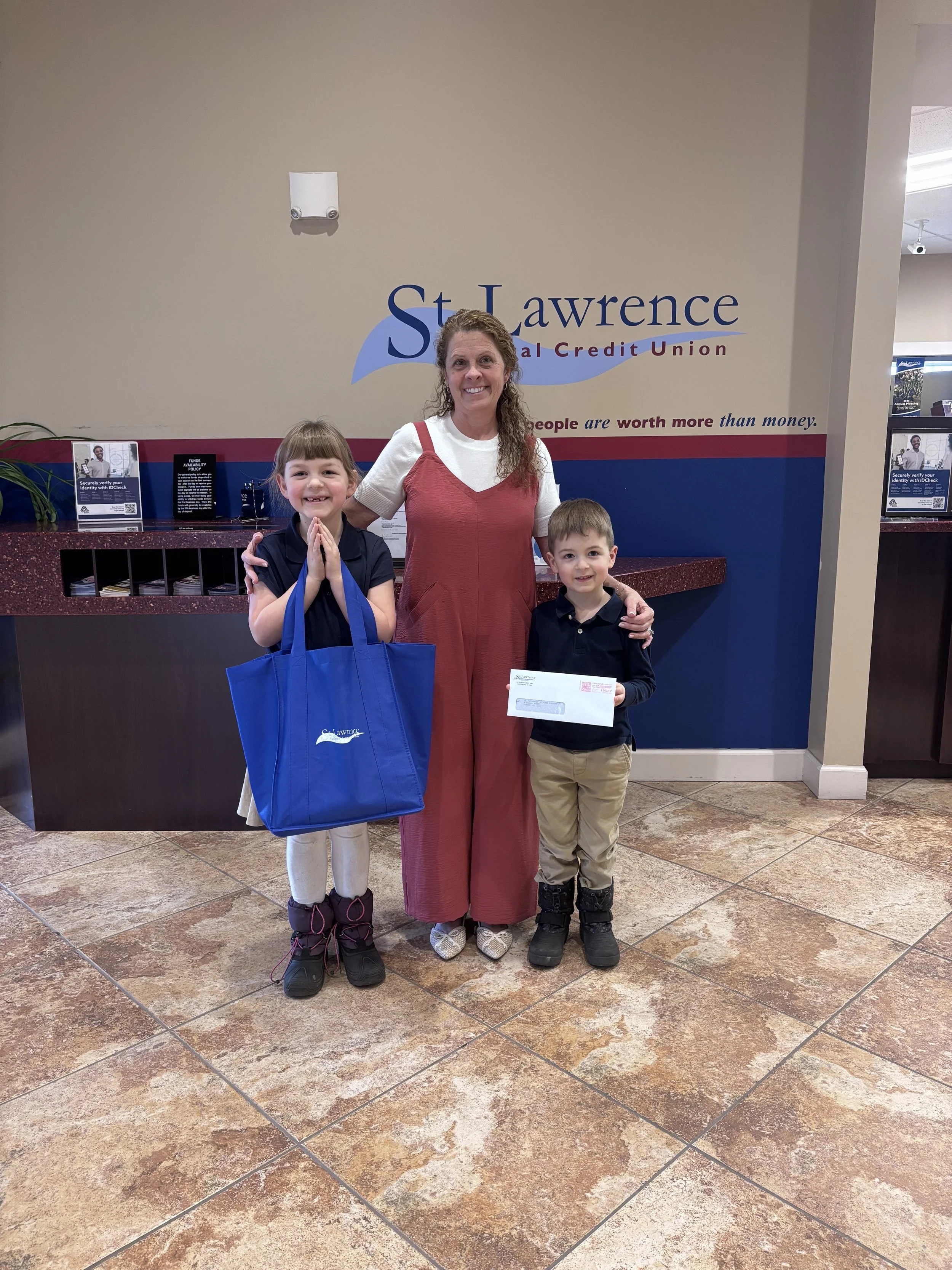 Adult female giving donation to two young children, one male and one female, for St. Catherine of Siena Academy located in Canton, NY.