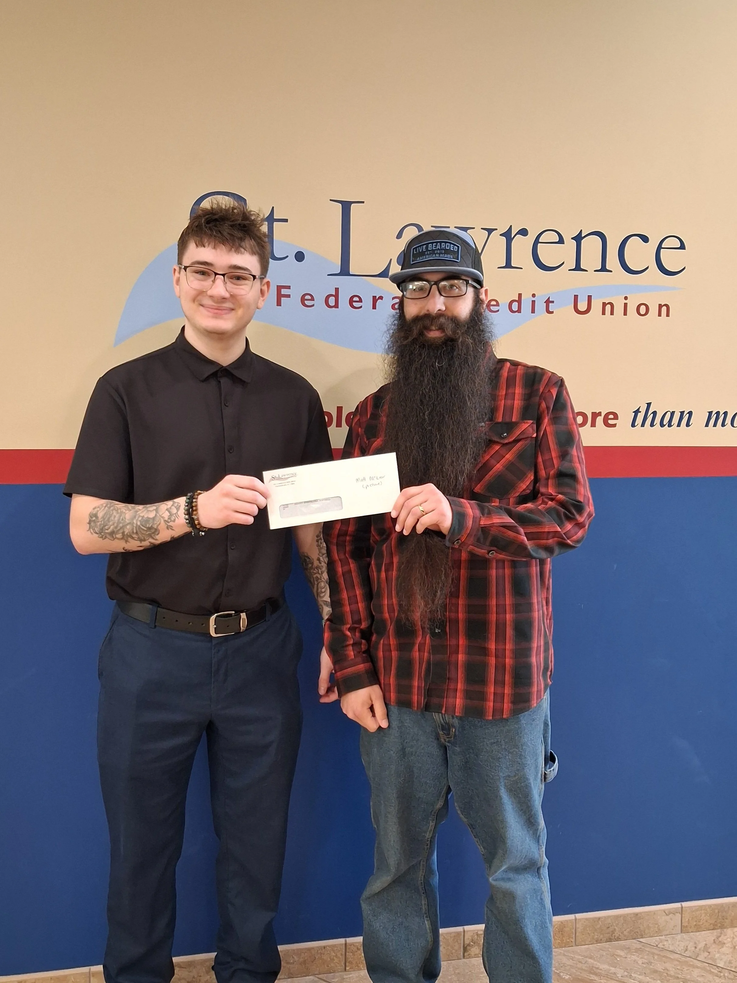 Young adult male presenting a donation check to an adult male fr a local softball program.