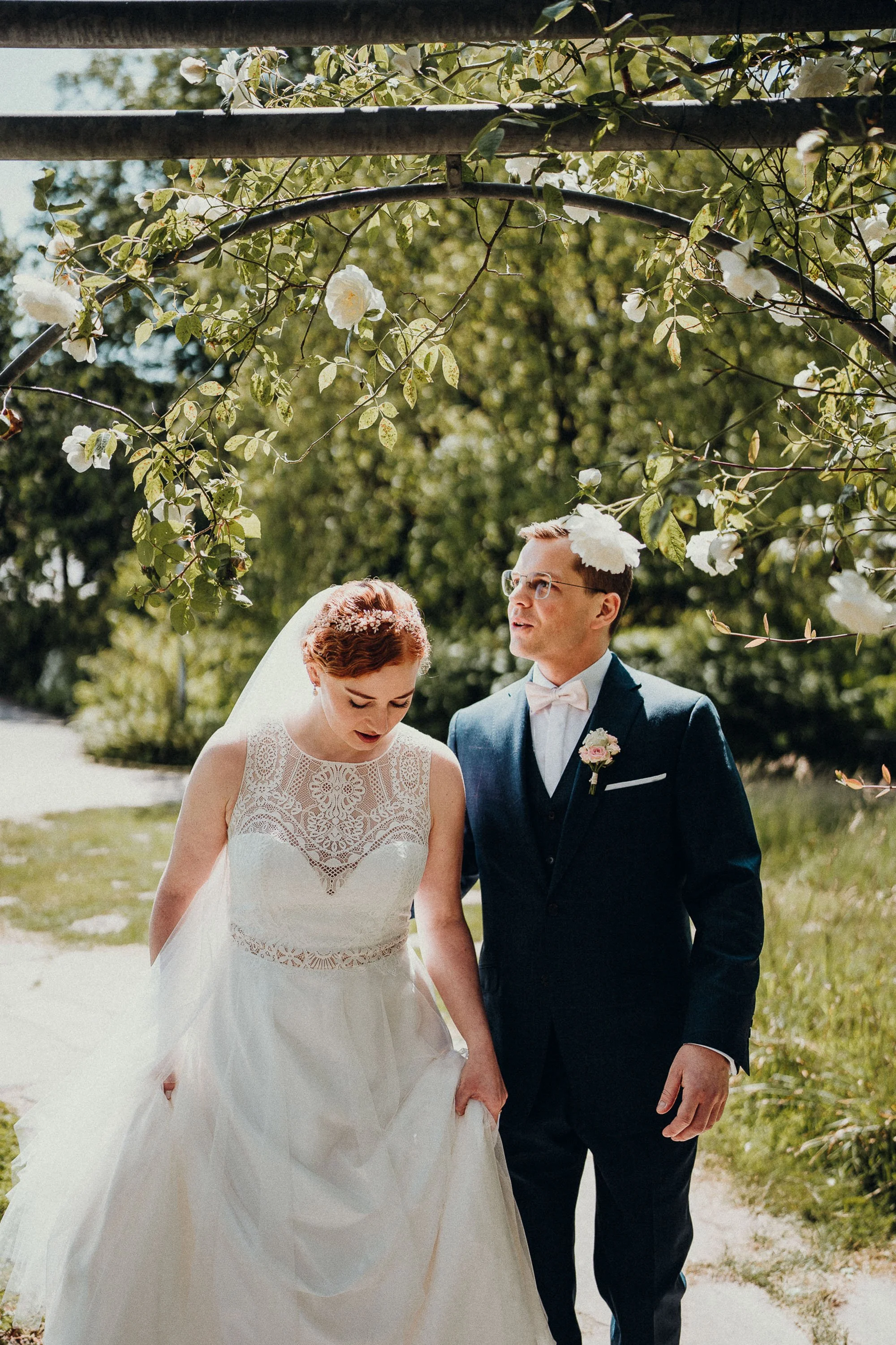 Brautpaar in Hochzeitskleidung unter blühenden Zweigen im Garten