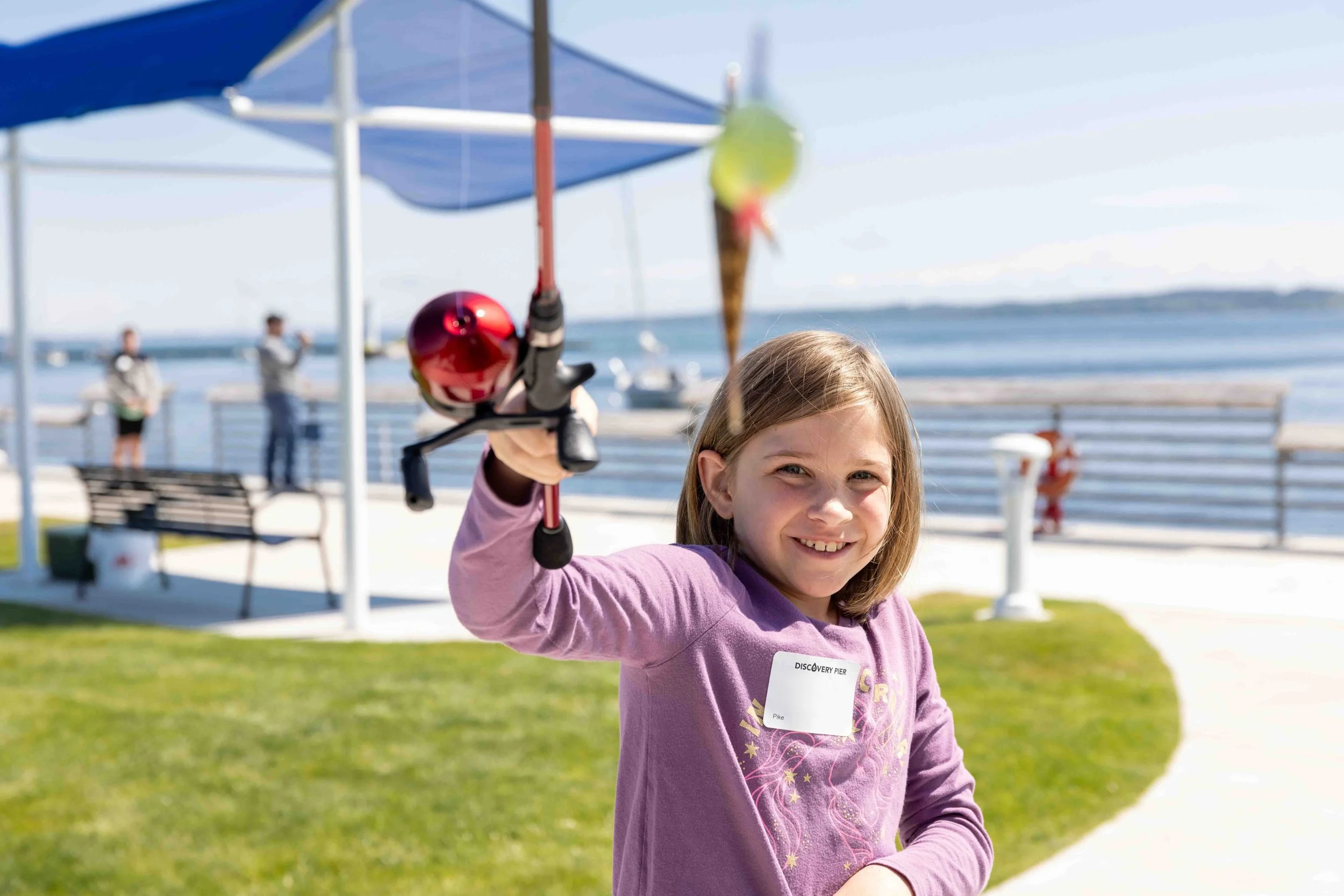 Child smiled while holding a rod with a hooked fish