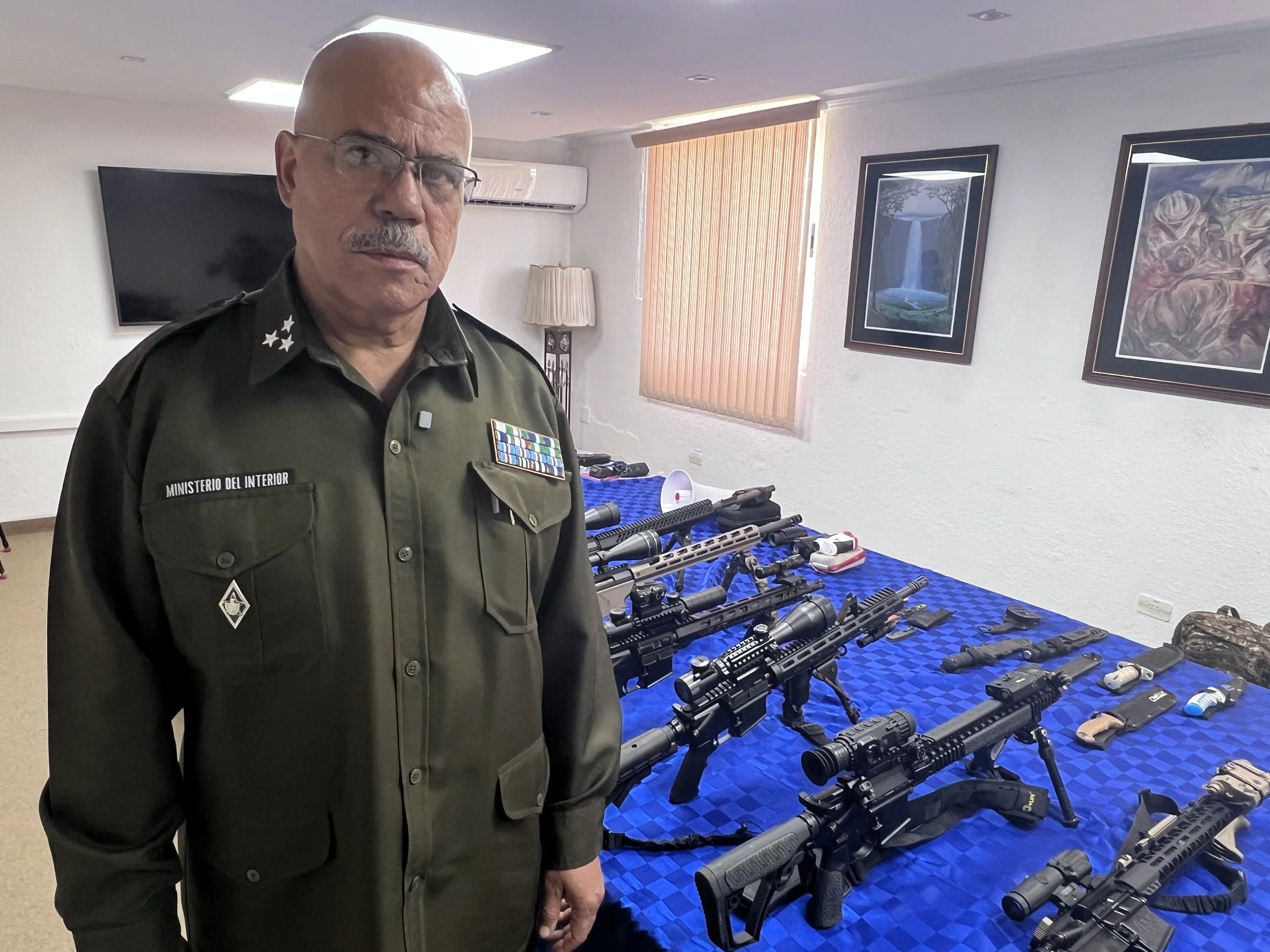 Colonel Francisco Estrada Portales, who heads the Interior Ministry's investigations into crimes against natoinal security, stands beside firearms Cuban authorities say were recovered from the boats.