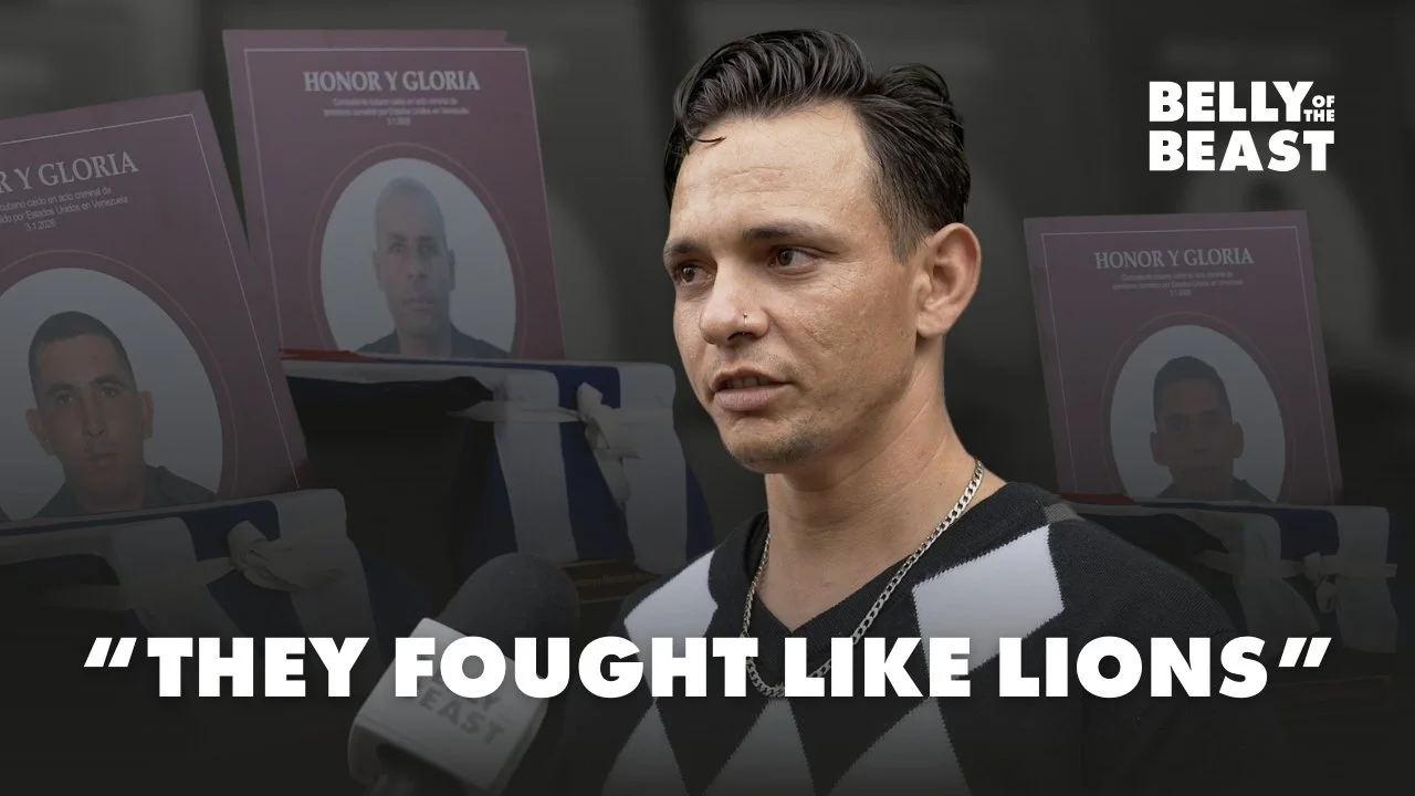 Cuban stands in Havana in front of memorial posters honoring Cubans killed in a U.S. attack, with the text “They Fought Like Lions” displayed on screen
