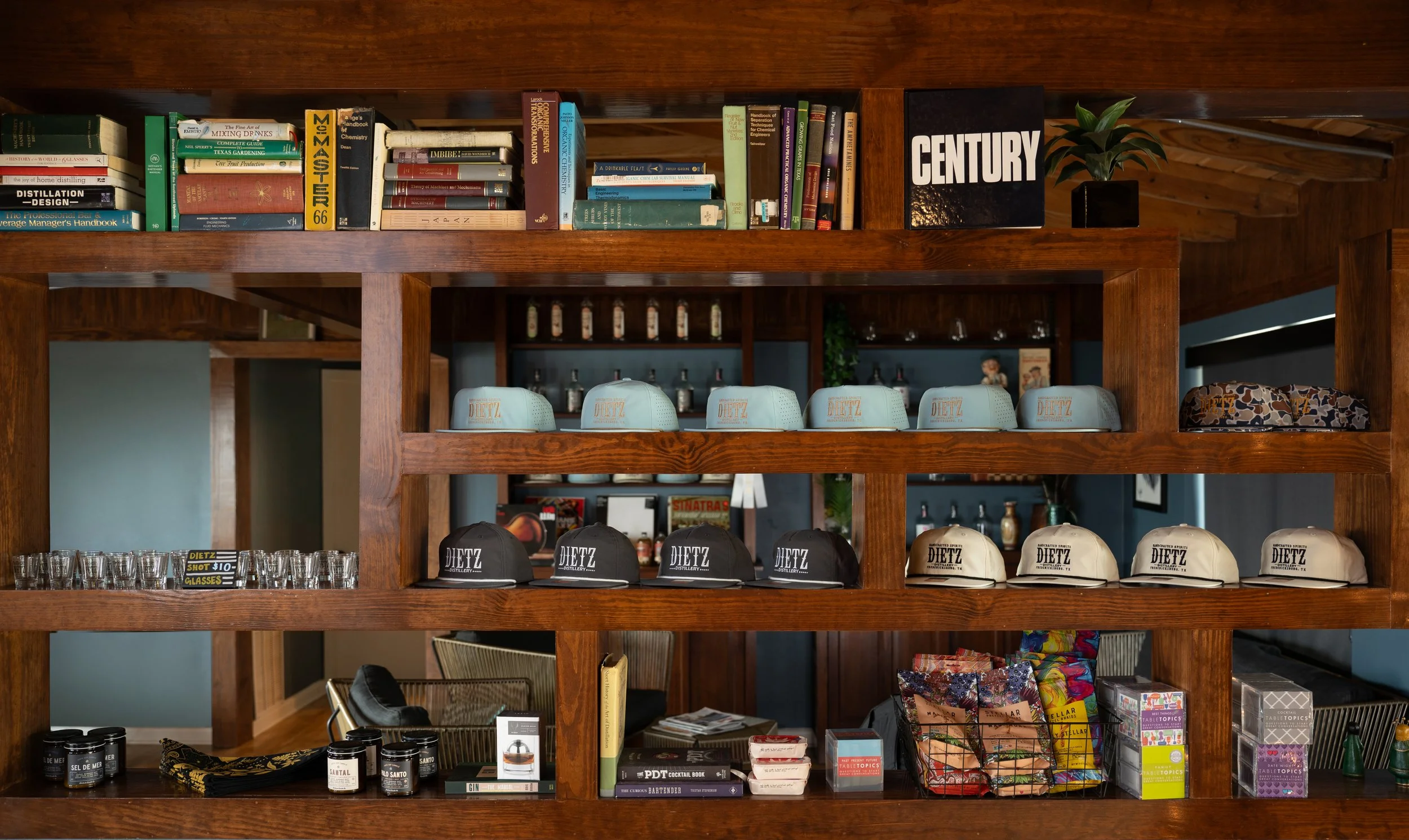 Wooden shelf displaying books, glasses, caps with 'Dietz' logo, and various beverages and products.