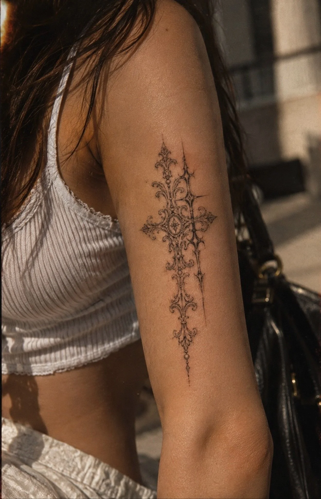 Ornamental cross tattoo with chains on upper arm at Studio Vanassa in Edmonton