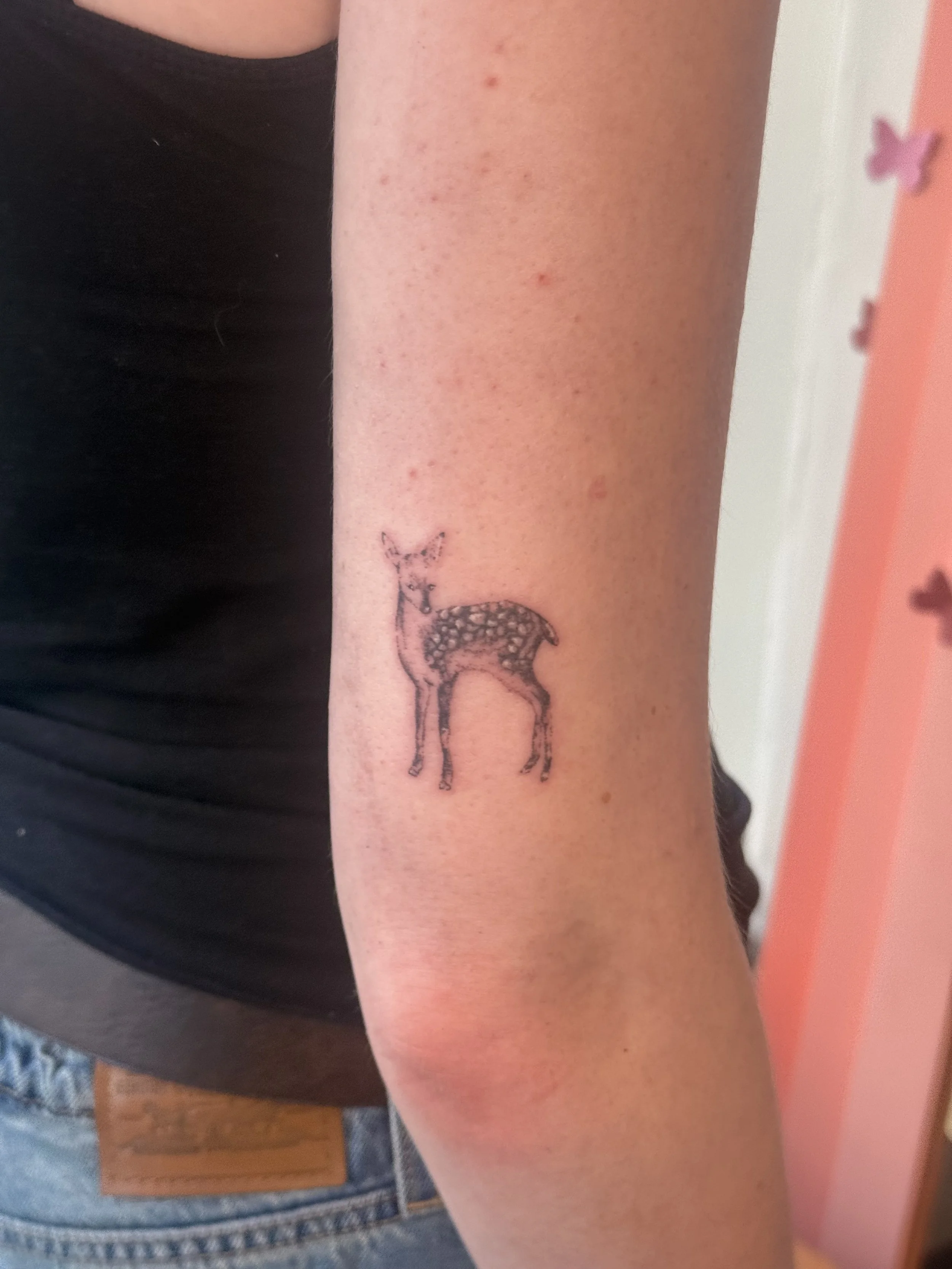 Small fine-line deer tattoo on the upper arm above the elbow at Studio Vanassa in Edmonton