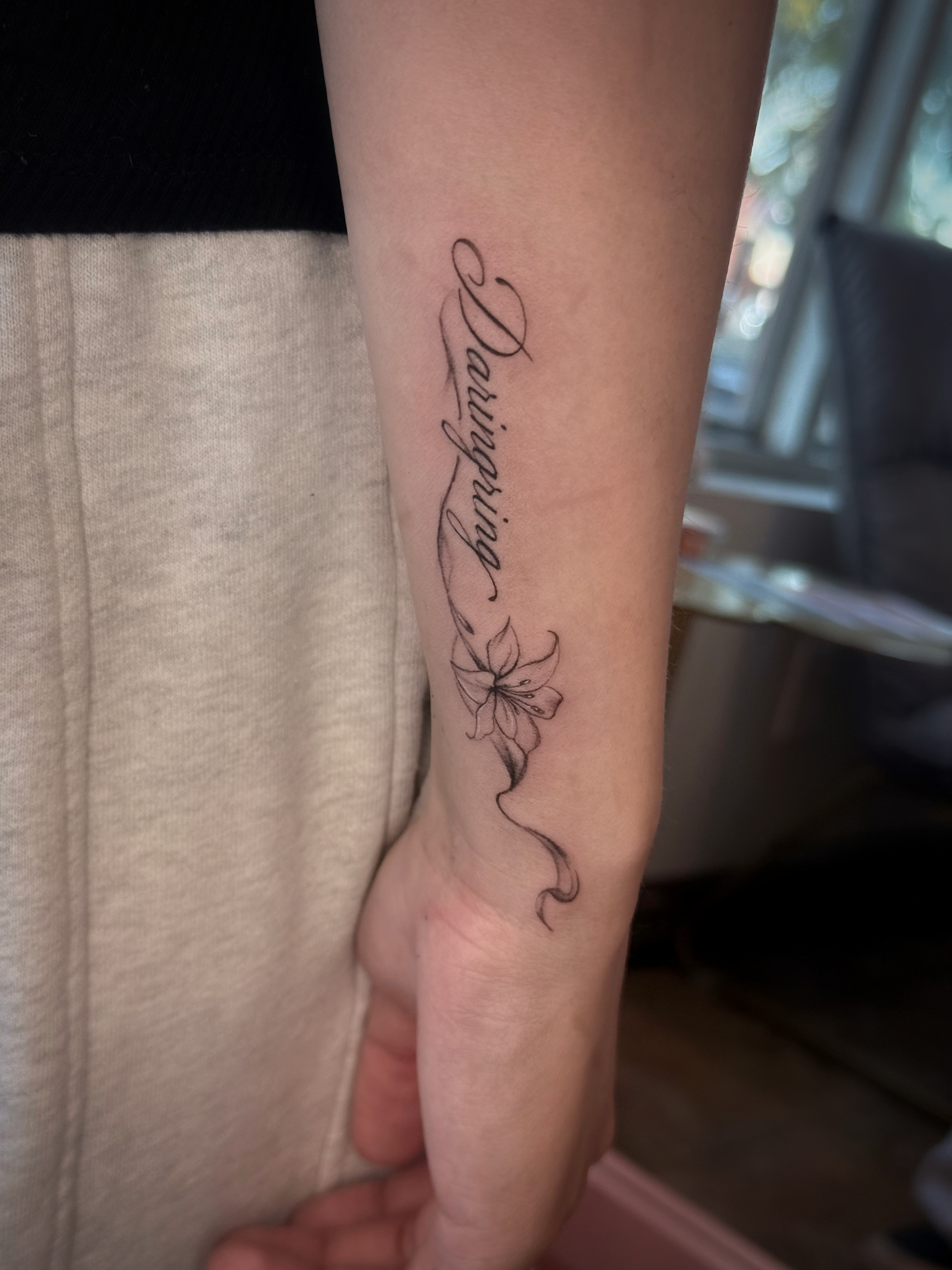 Fine-line script tattoo with a small floral design on the inner forearm at Studio Vanassa in Edmonton