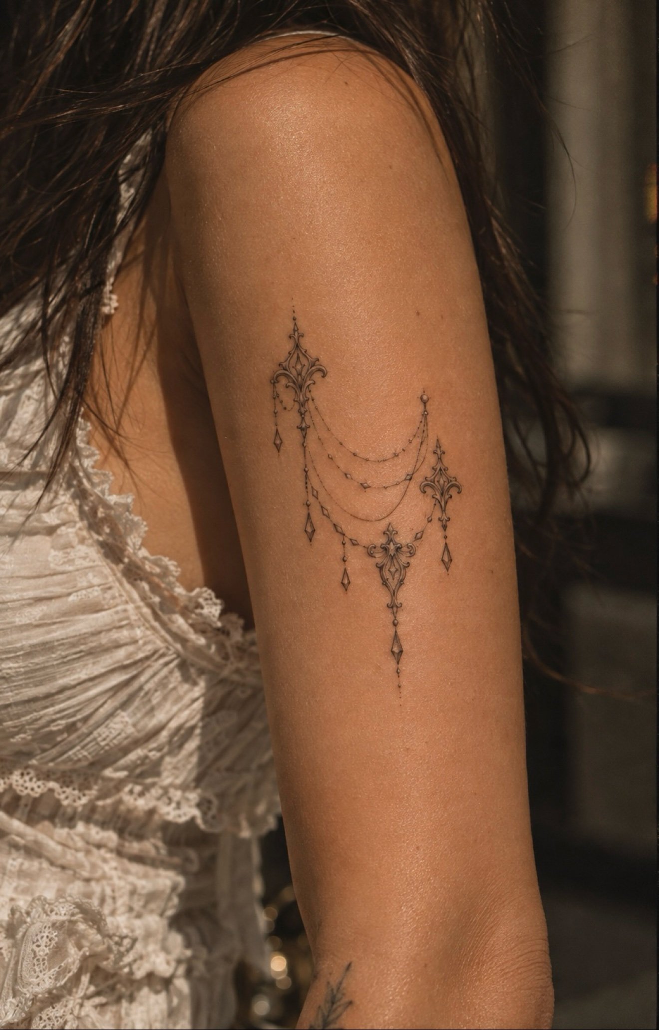Ornamental chain drape tattoo on upper arm at Studio Vanassa in Edmonton