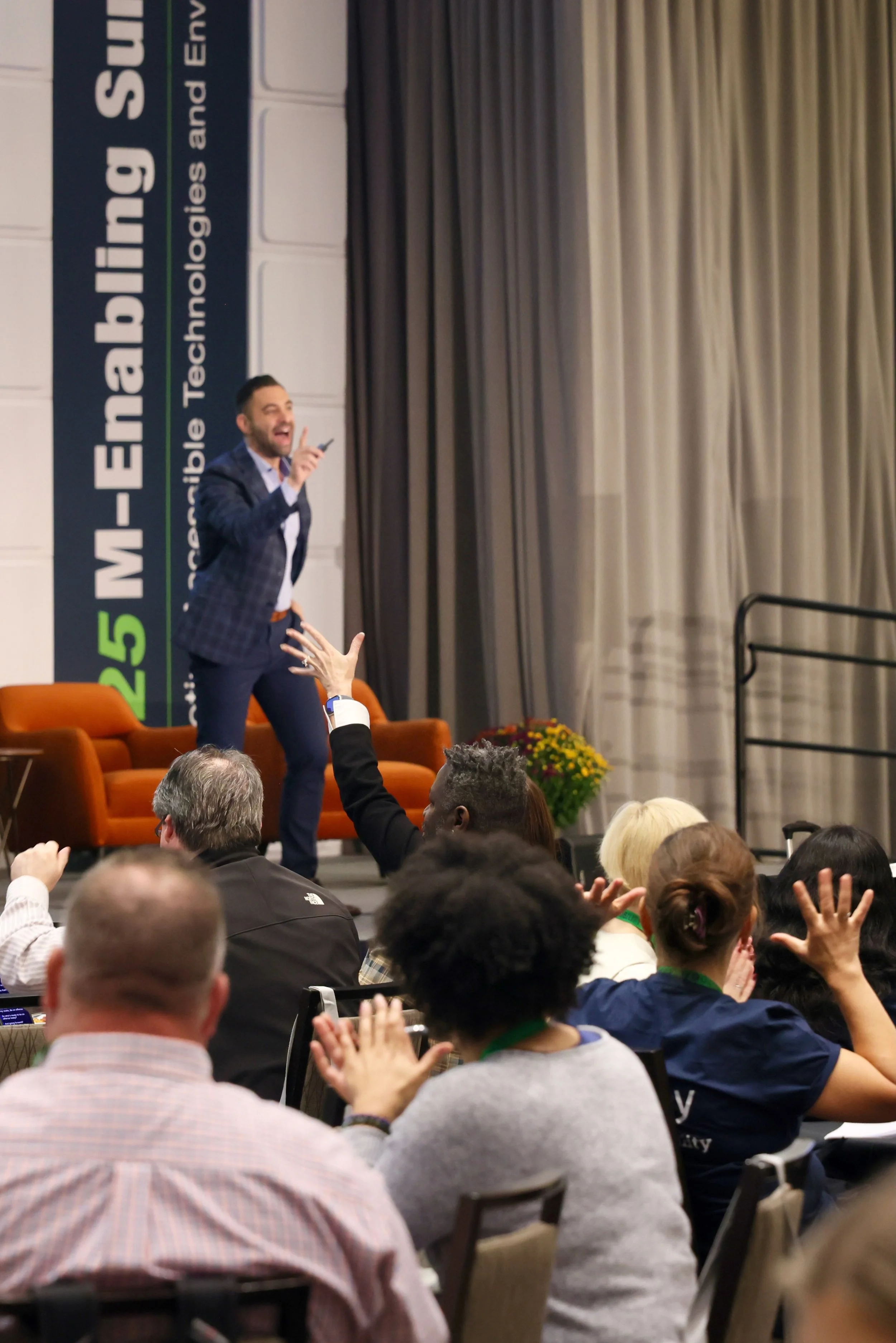 A photo of Dustin on a stage in front of 500+ people (most are seen in the image)