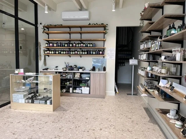 Interior of a retail store with shelves of products, a display case, and a staircase in the background.