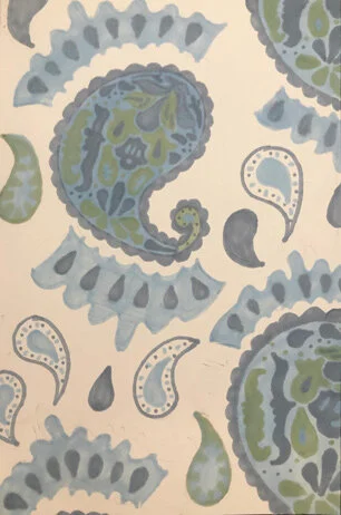 Close-up of a fabric with a paisley pattern in shades of blue, green, and gray on a white background.
