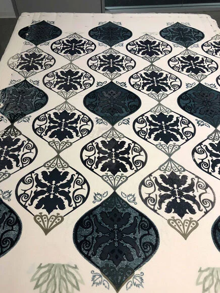 A patterned rug with black and white floral and geometric designs arranged in a symmetrical diamond shape.