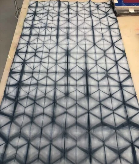 A fabric or material with a geometric pattern of interconnected black lines creating star-shaped and hexagon shapes.