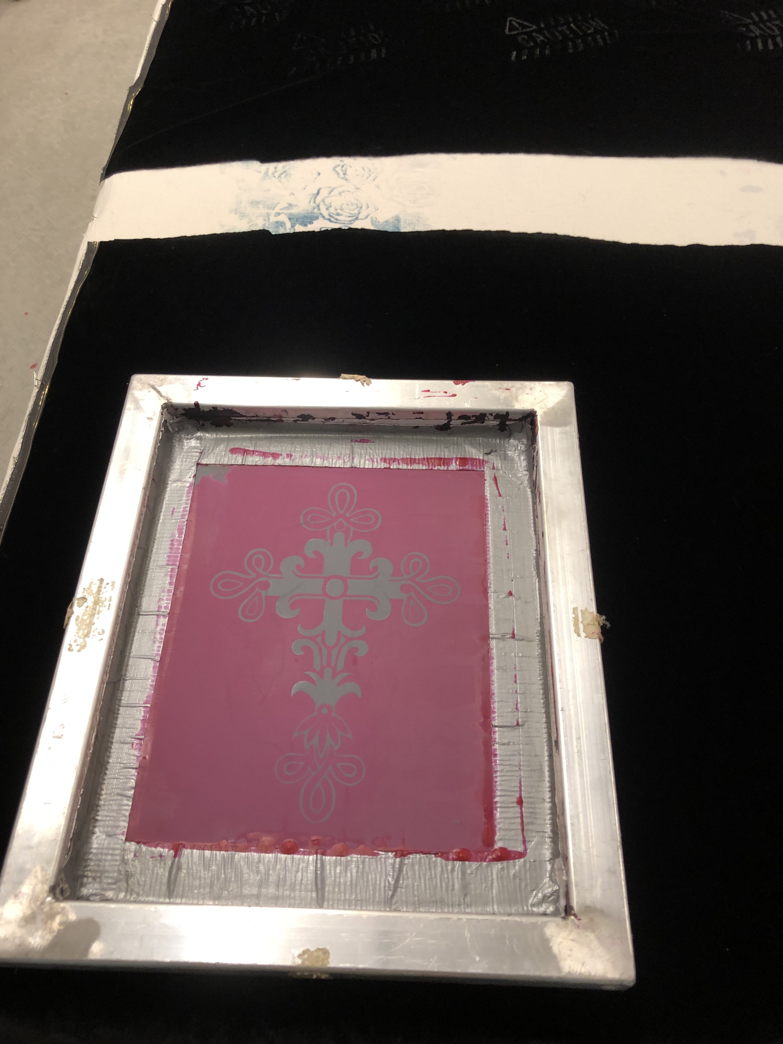 A metallic mold with pink silicone, displaying a symmetrical decorative pattern, placed on a black surface.