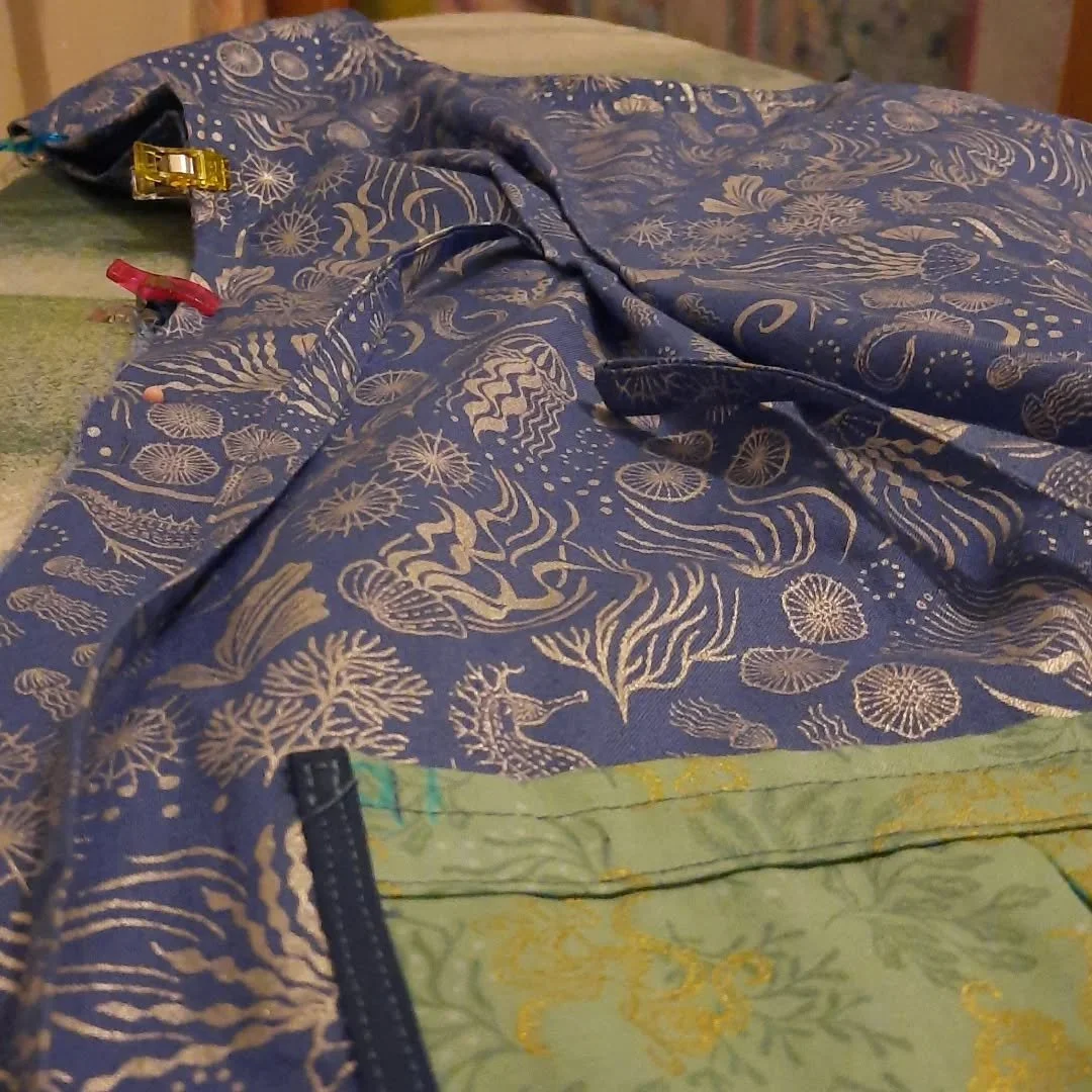 Just the french seam to go!

Image description: A dress in the making is visible from a funny angle, based at the dresses pocket and looking up. Some pins and fabric pegs hold the fabric (blue with silver nautical motifs) together.

#artpractice #art