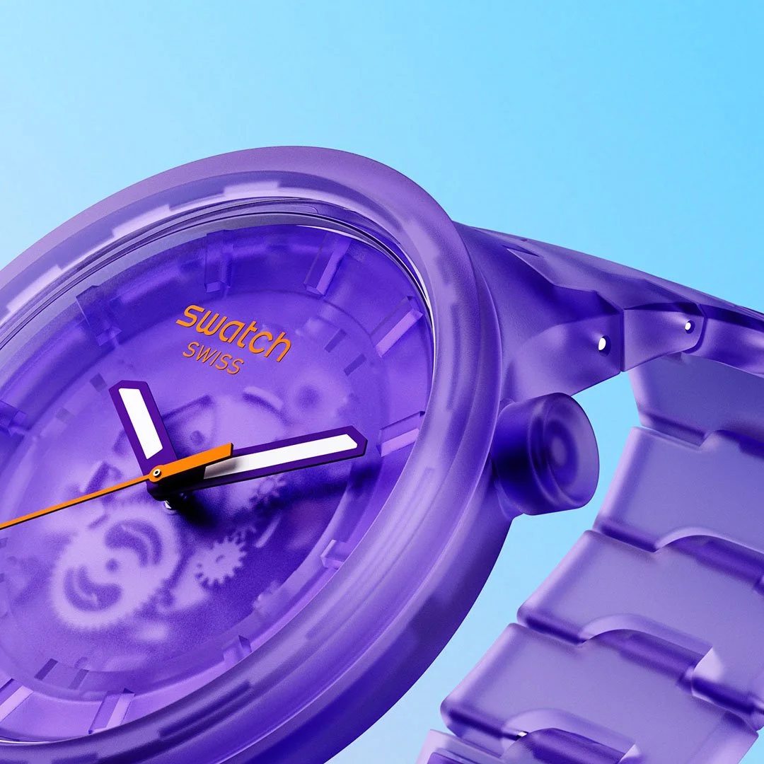 Close-up of a purple Swatch Swiss watch with a transparent face and band against a blue background.