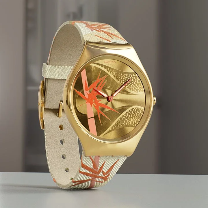 A gold wristwatch with a beige strap and an abstract orange and beige design on the face.
