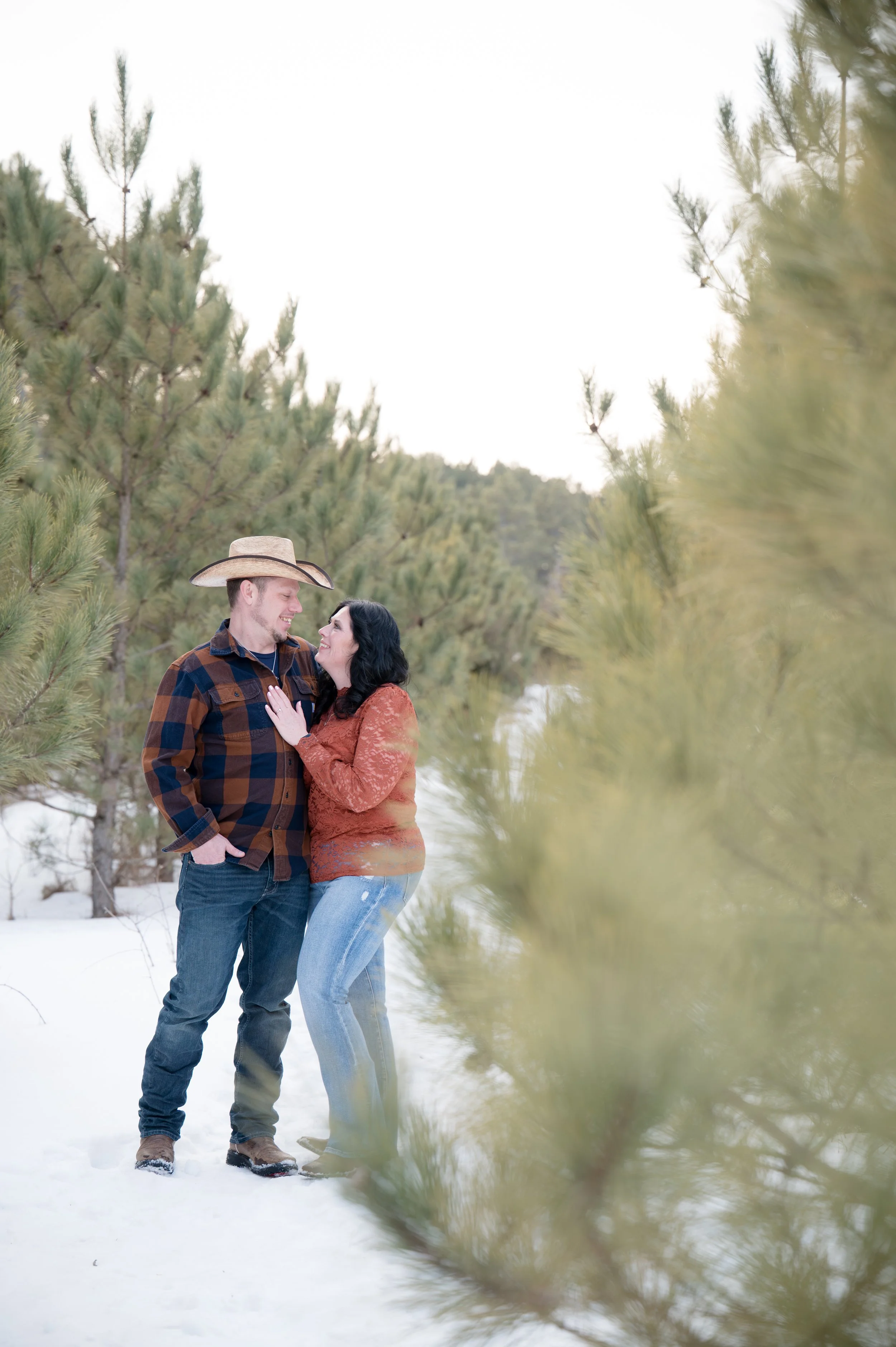 Romantic couple embracing in a winter background including pine trees.