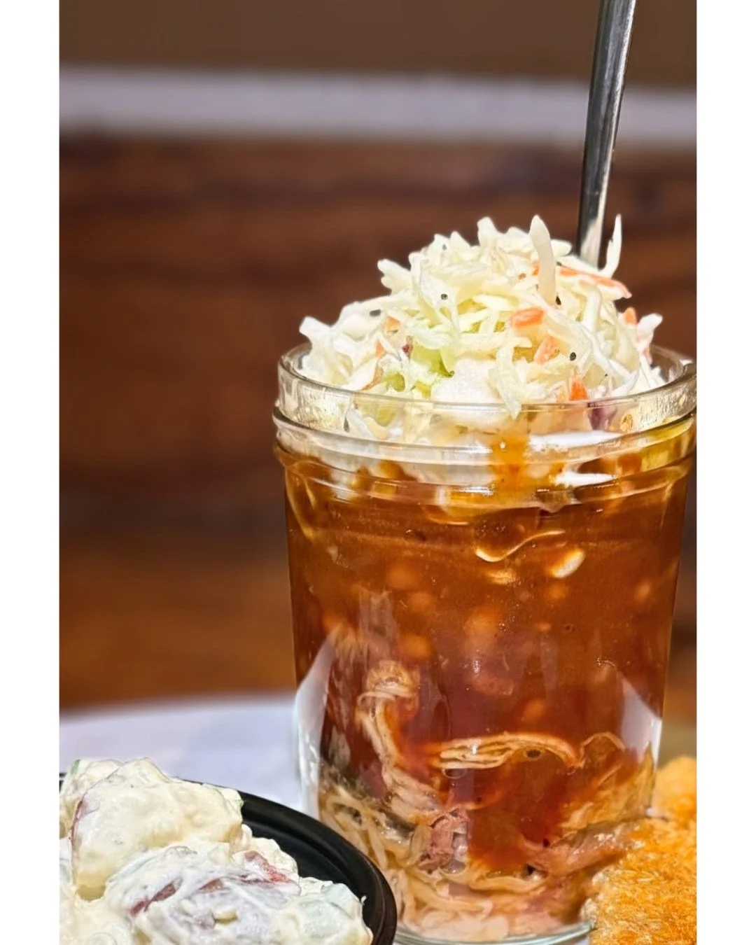 🔥 Craving something unique and delicious? Dive into our BBQ Sundae! Layers of tender pulled pork, savory bacon &amp; brisket bbq beans, and our signature BBQ sauce, all topped with a crunchy coleslaw crown. It's the ultimate comfort food experience 