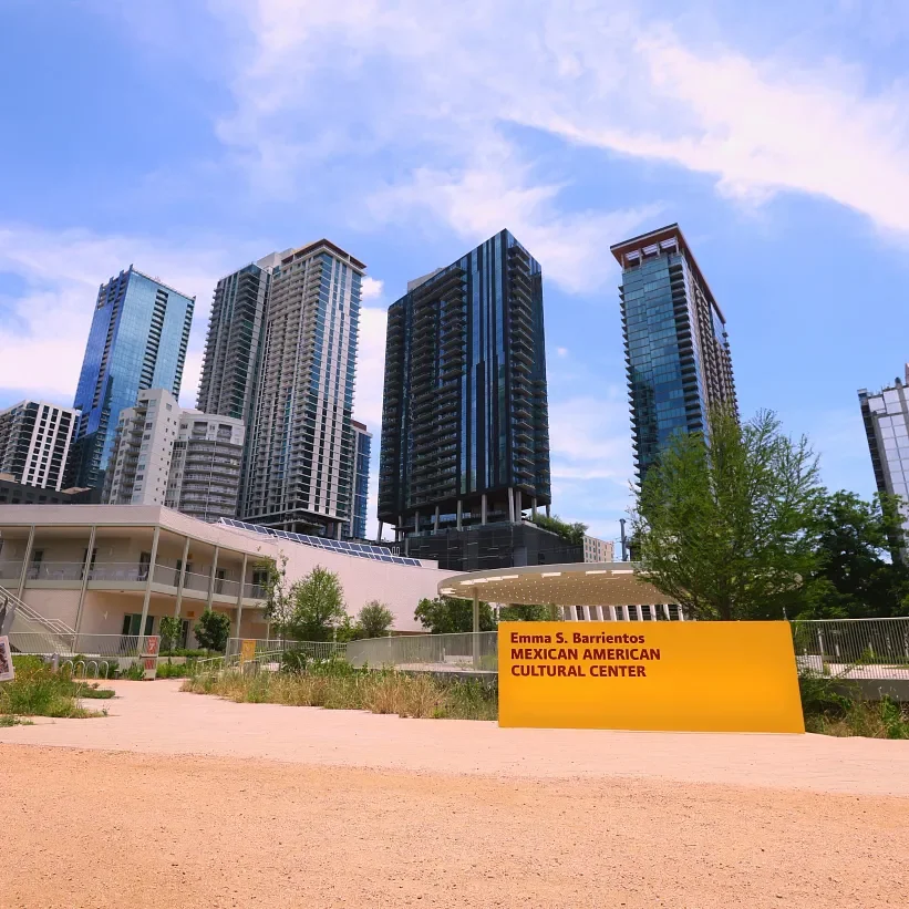 A short white building in front of many skyscapers