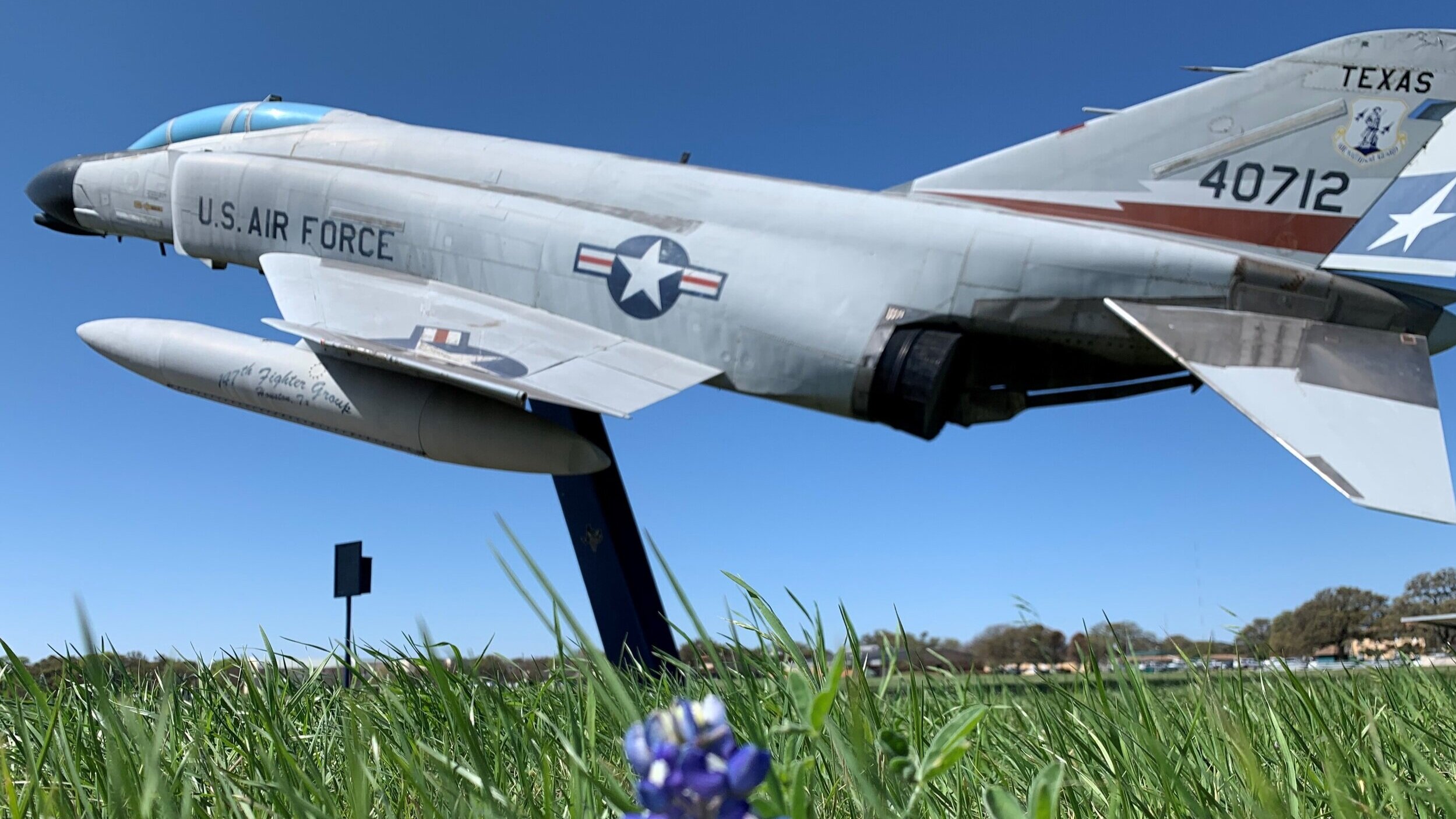 A military plane on display outside in a field.