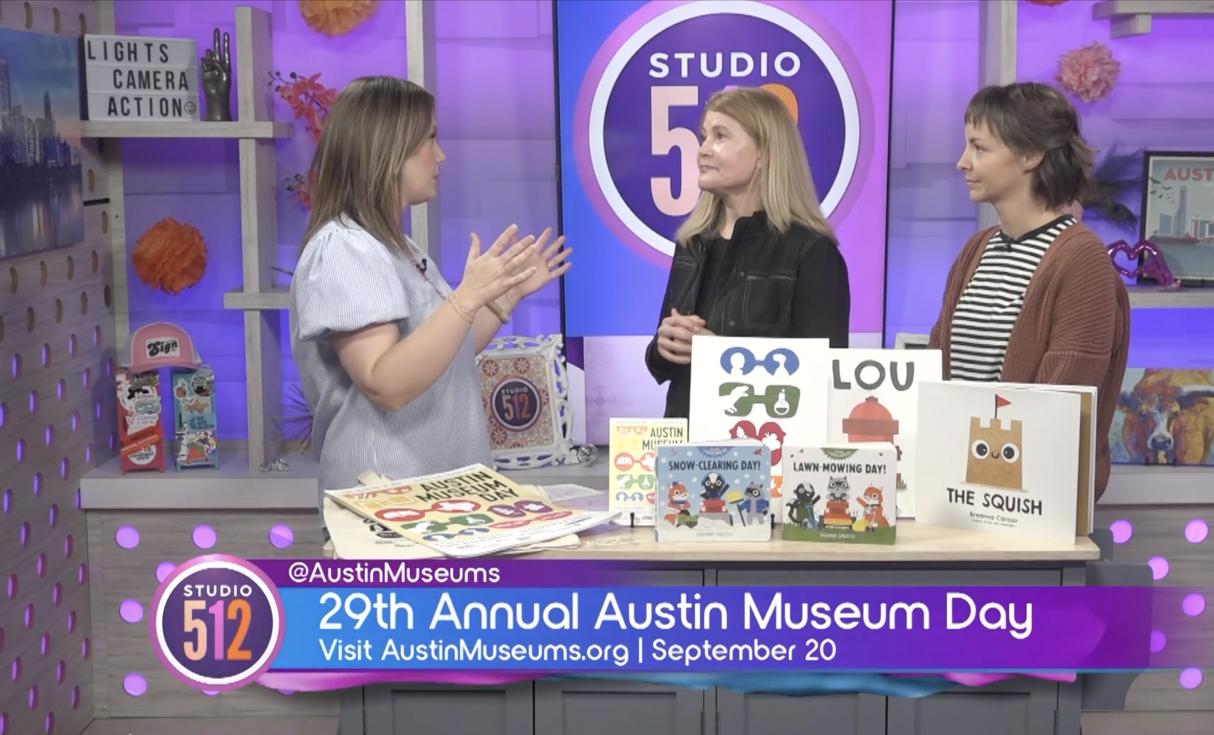 Three adults standing in a news studio behind a table that has children's books on it. Text at the bottom reads 29th Annual Austin Museum Day Visit AustinMuseums.org