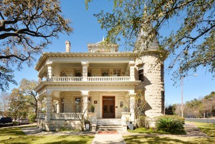 Exterior of an historic cream colored historic stone house with a tower