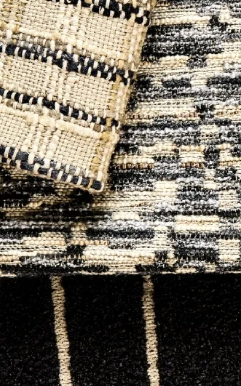 Close-up of a patterned, textured fabric with a woven design in black, beige, and off-white colors.