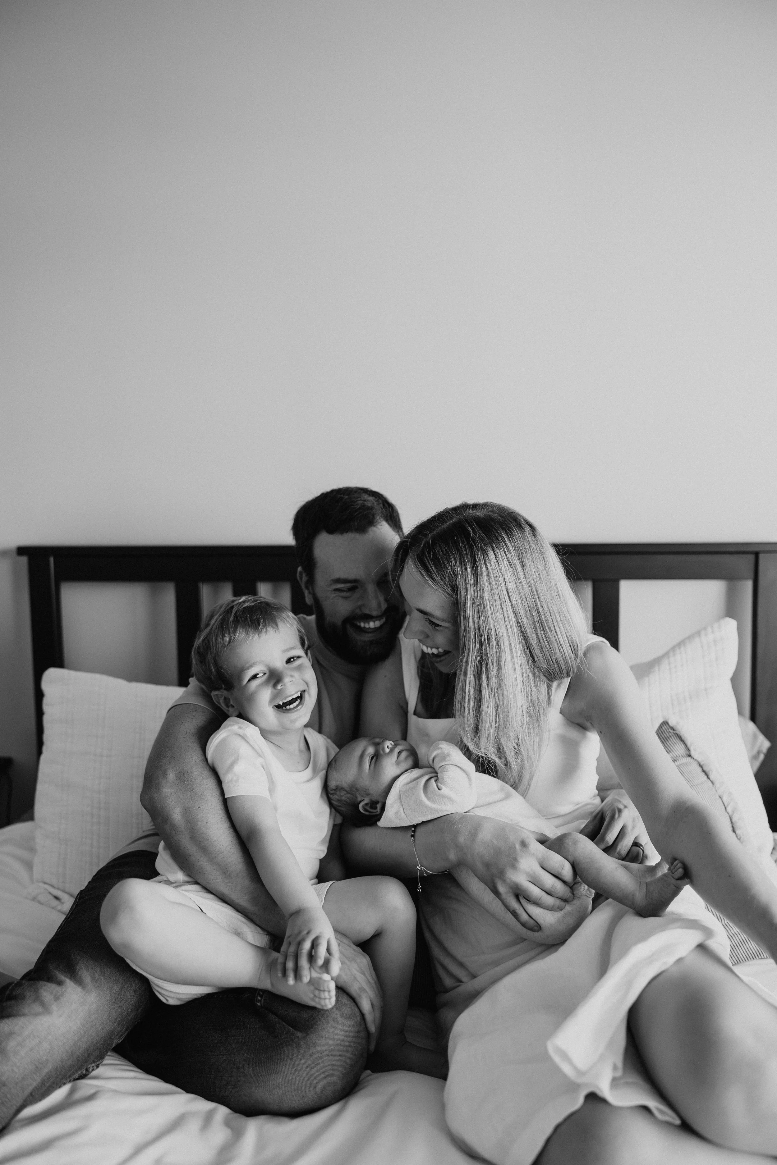 Parents pose with toddler and newborn