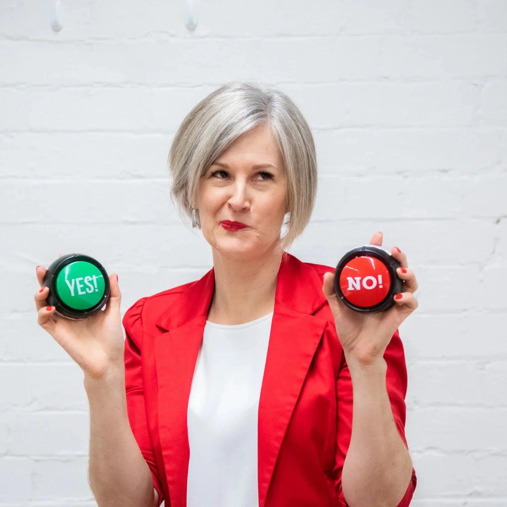 Anna holding a green 'YES' button in one hand and a red 'NO' button in the other, with a quizzical expression.