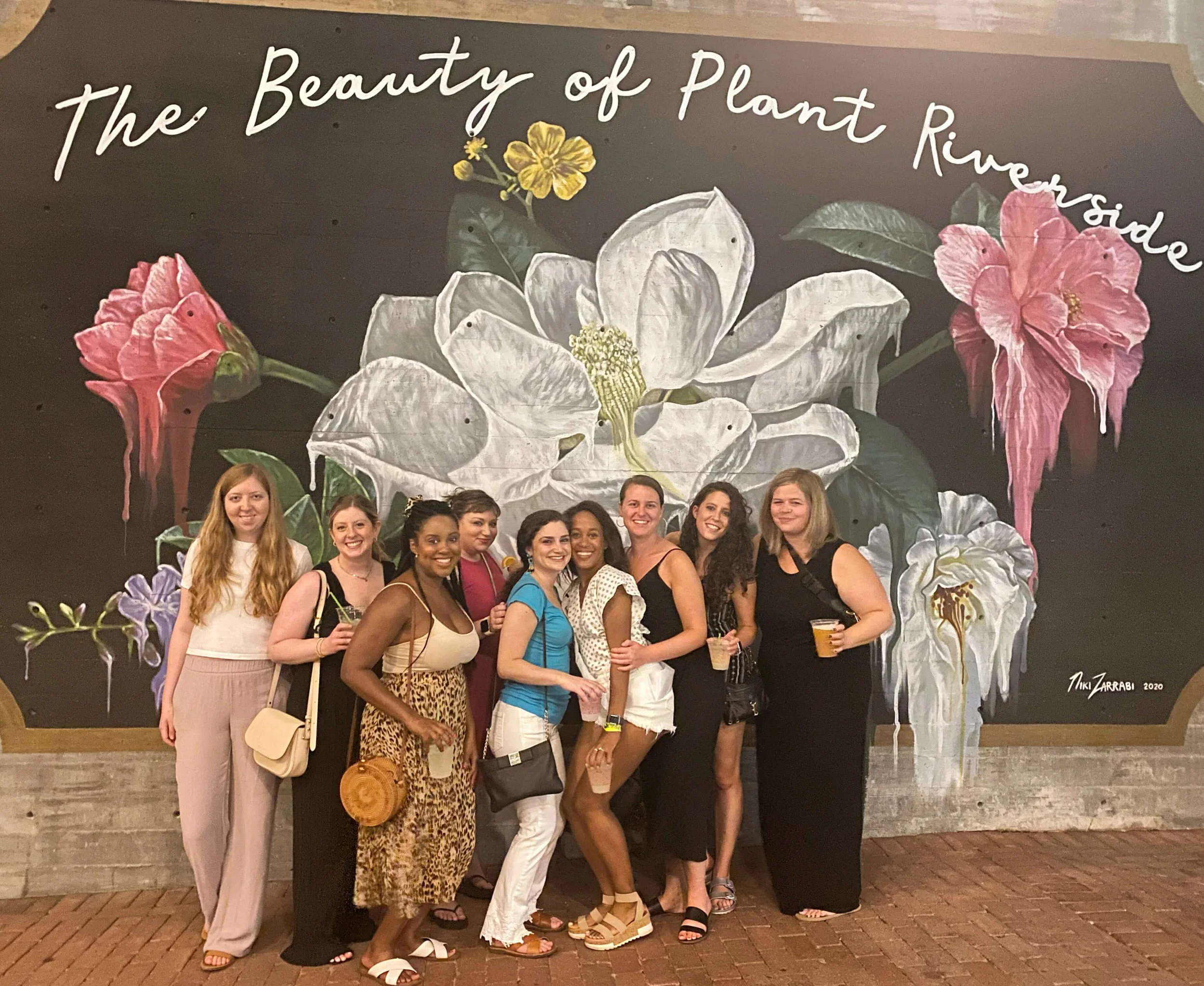 Group of girls posing in front of a mural in the Plant Riverside district