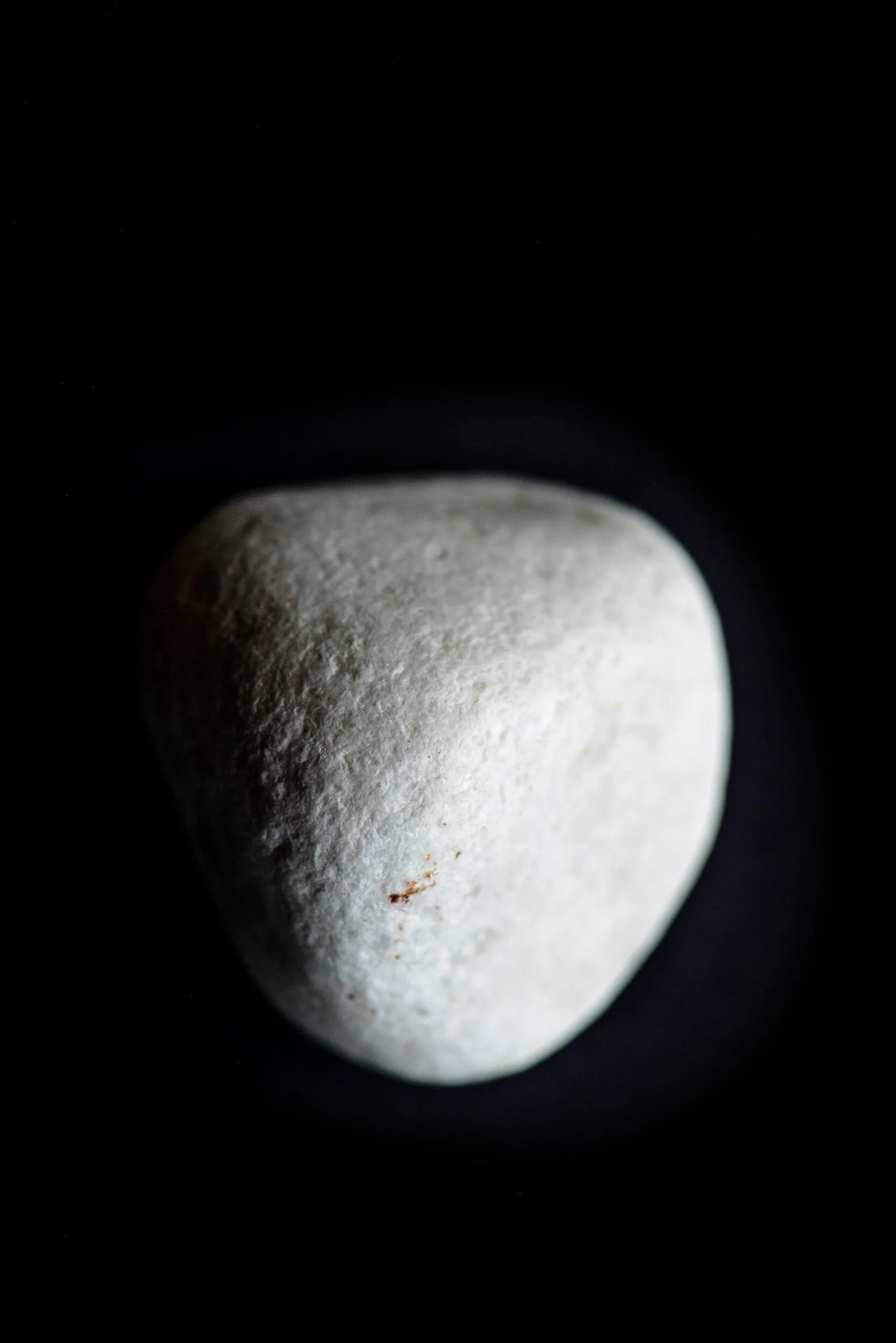 Close-up of a smooth, white stone on a black background.