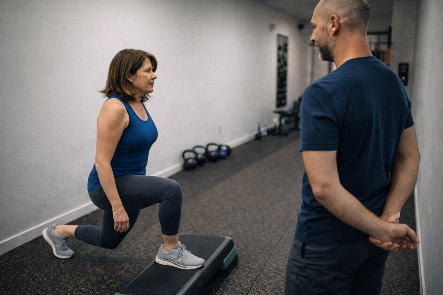 Personal trainer in Toronto observing a client performing a split squat during a knee pain movement assessment.
