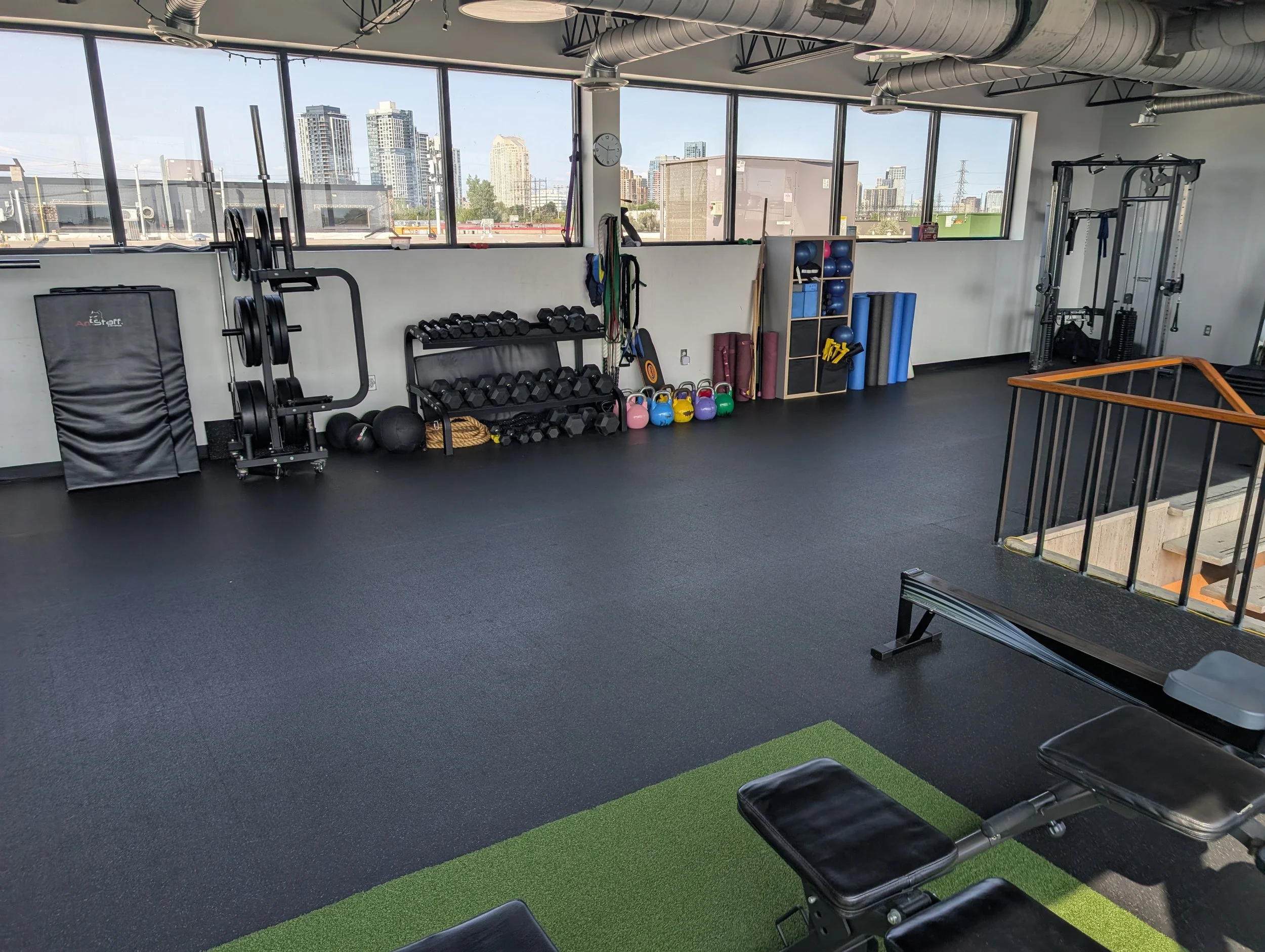 Wide interior photo of the Unified Health & Fitness private training studio with turf lane and strength equipment.