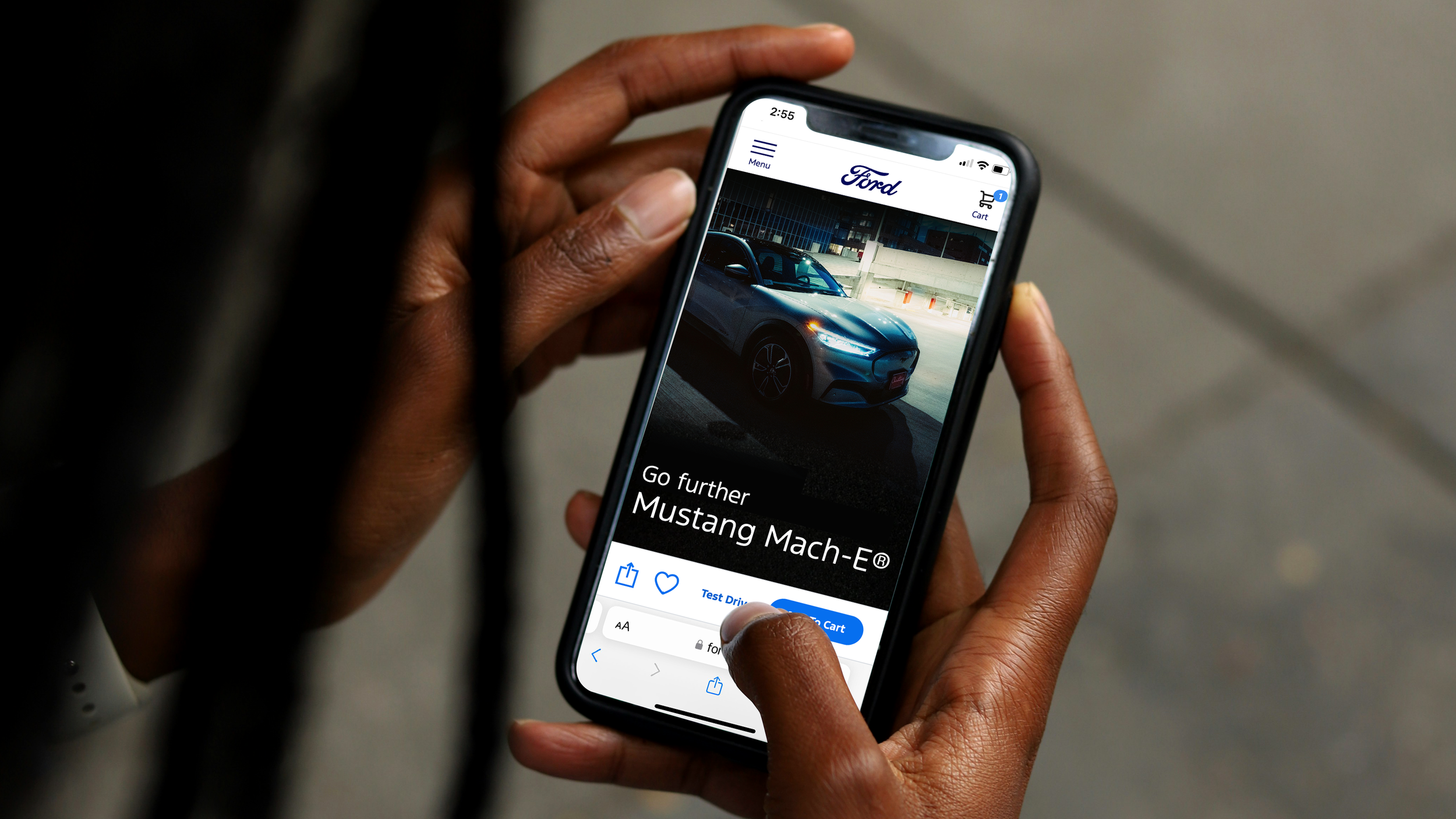 Close-up of a person's hand holding a smartphone displaying a car shopping app, showing a blue Mustang Mach-E in a parking lot.