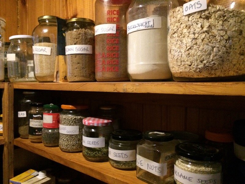 Labelled glass jars with dry goods on pantry shelves