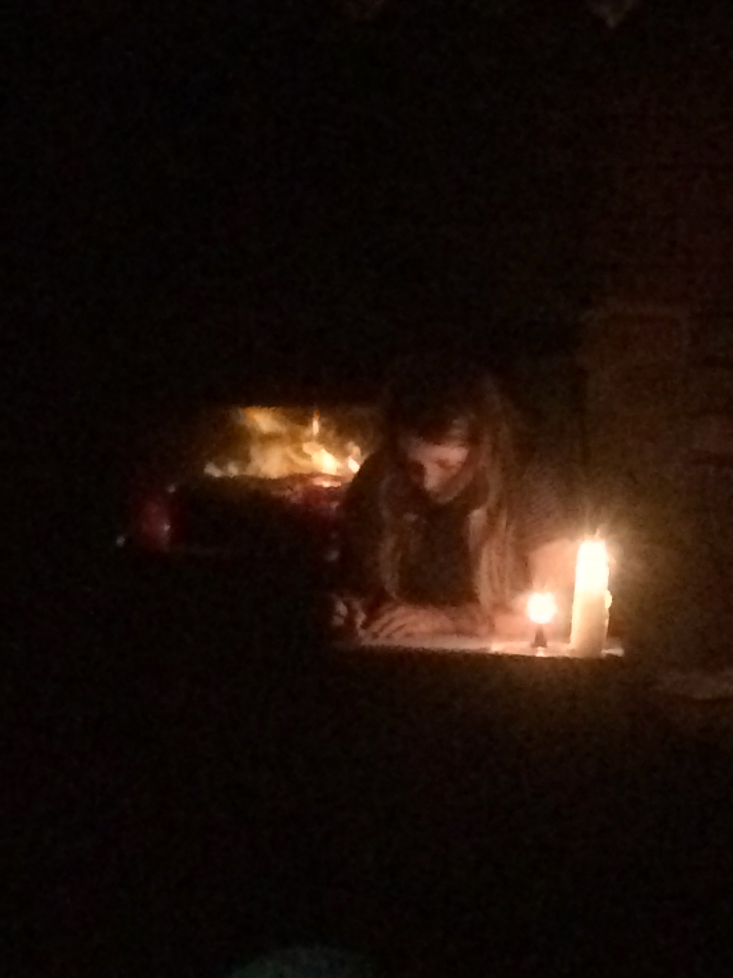 Girl with long hair writing by candlelight with fire behind
