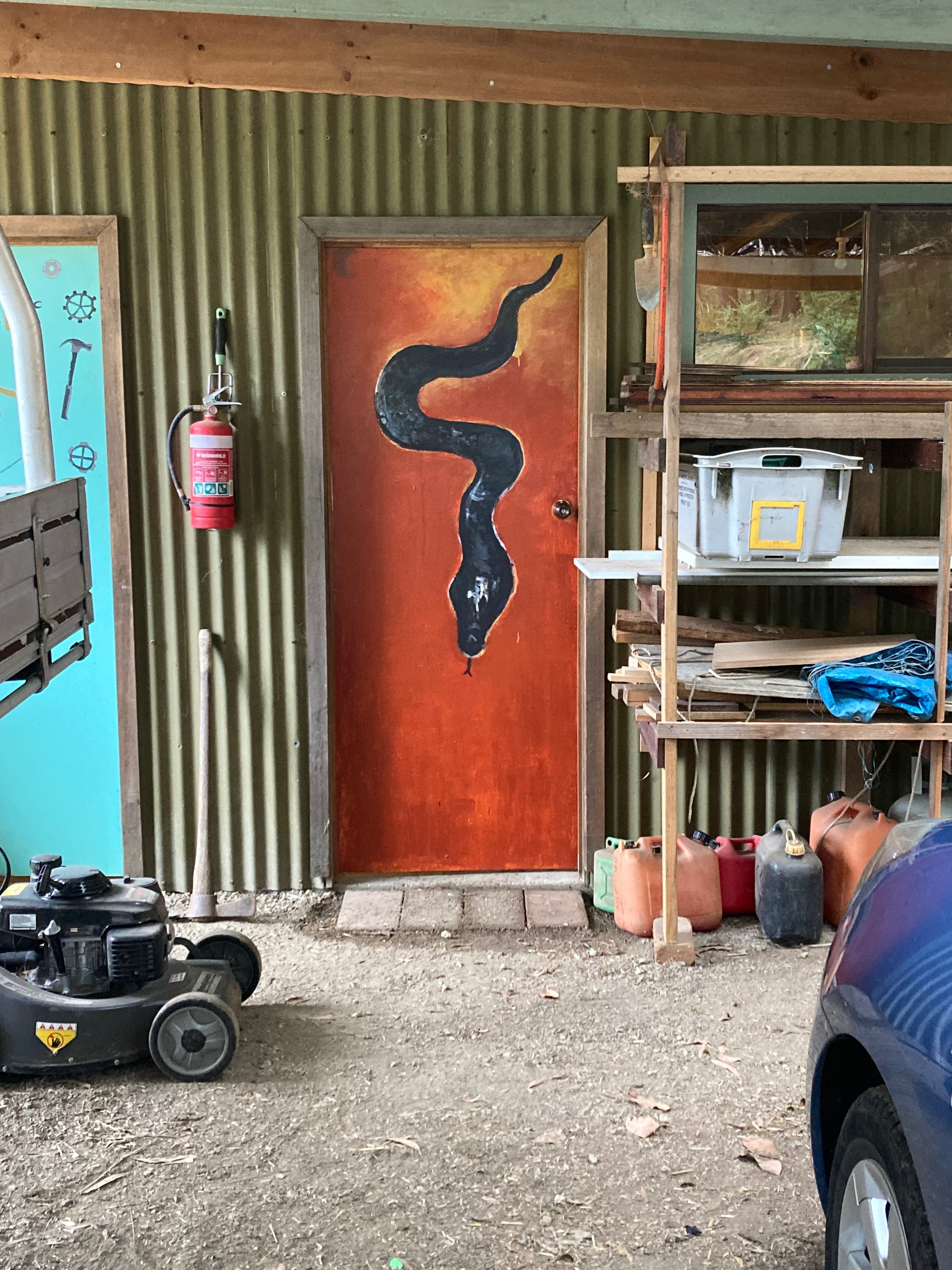 Shed door with painted black snake on bright orange background