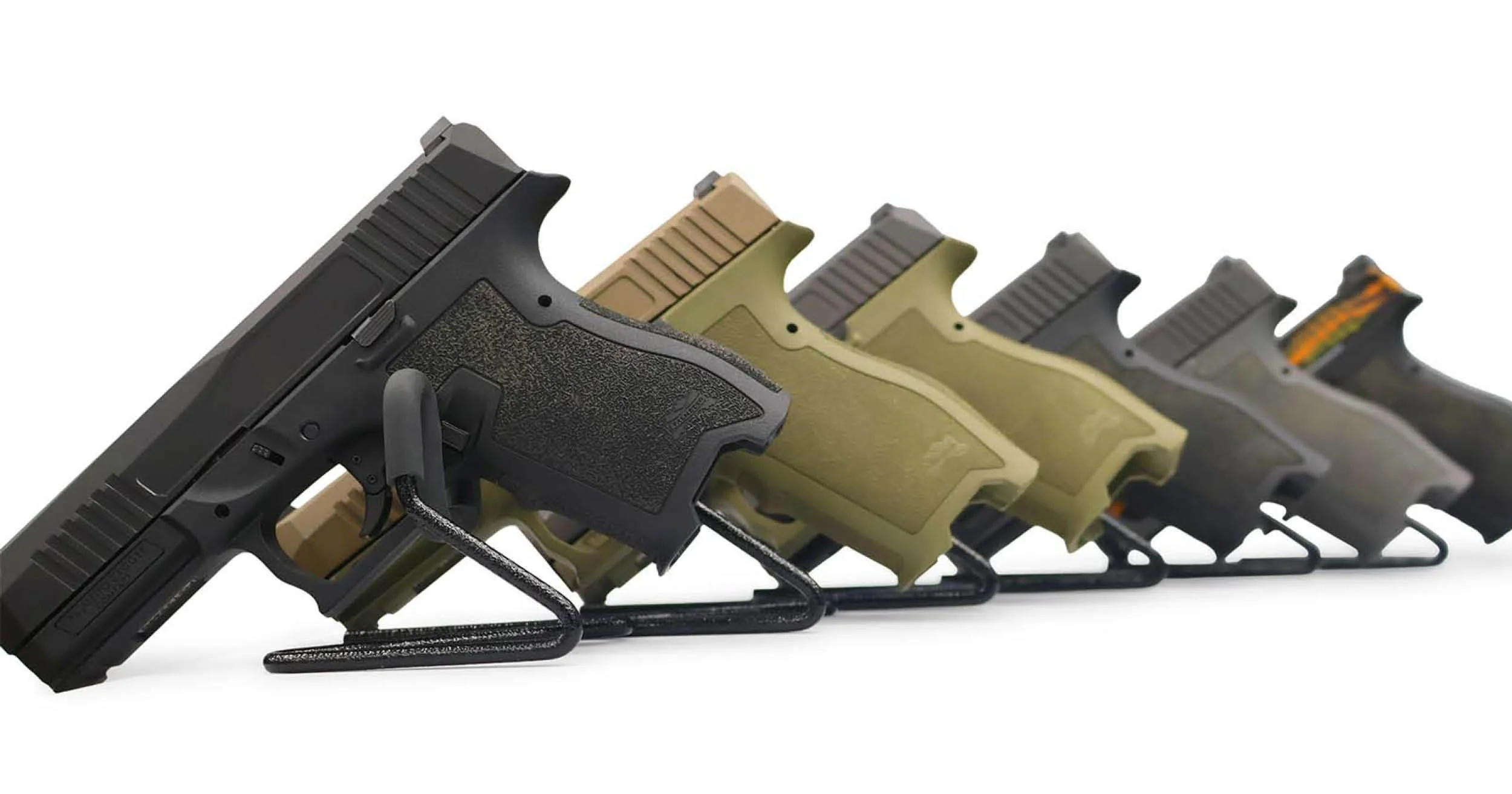 Six PSA Dagger Handguns in a row of varying colors of blackm green, and camo on a white background.