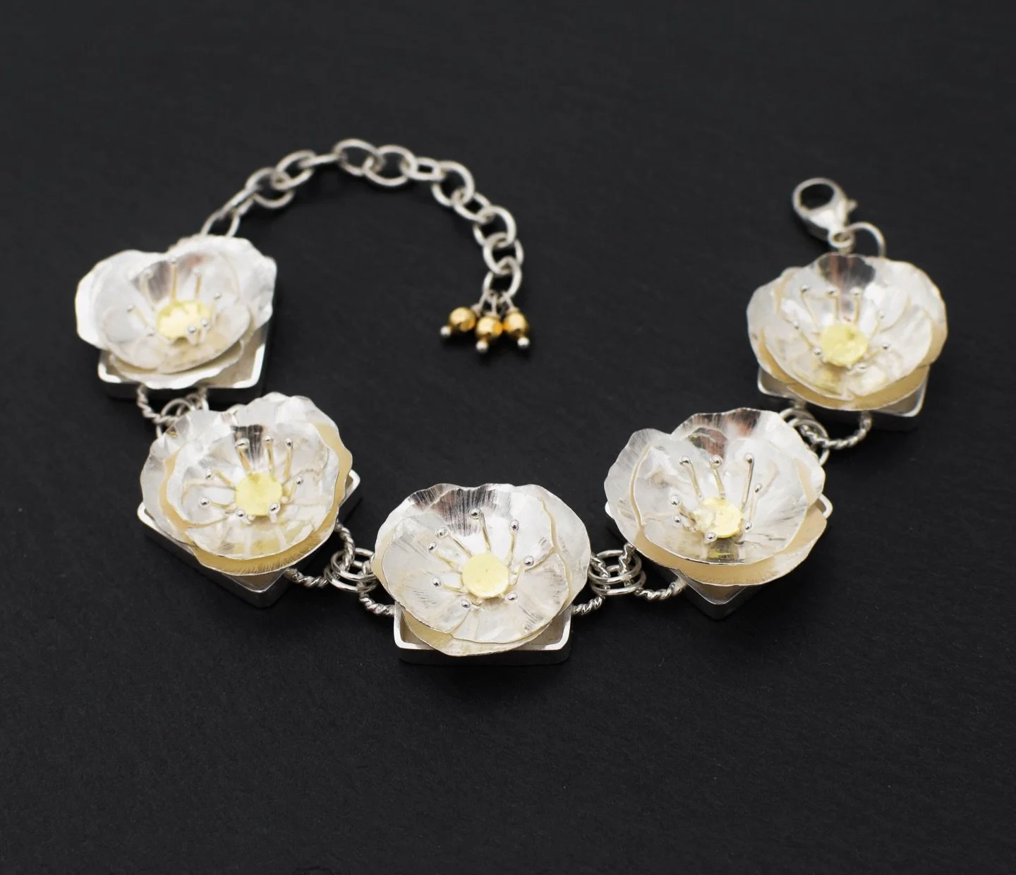 Poppy bracelet made with sterling silver and 18k gold accents, hand fabricated.

A series of sculpted floral forms, each one built individually and slightly different. #handfabricatedjewelry #poppies #handmadejewelry #metalsmith #handmadebracelet