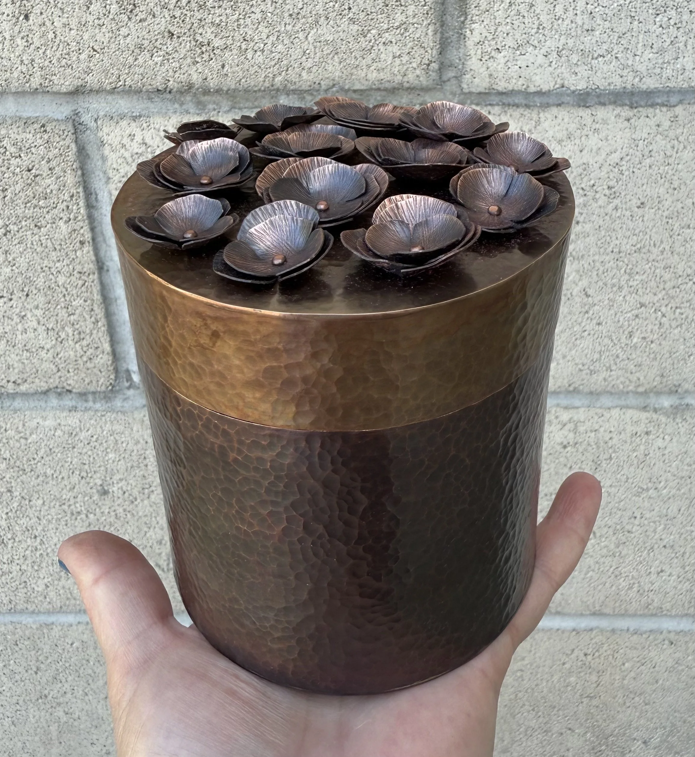 A copper container with copper poppies on the lid. Completely handcrafted from a sheet of copper.