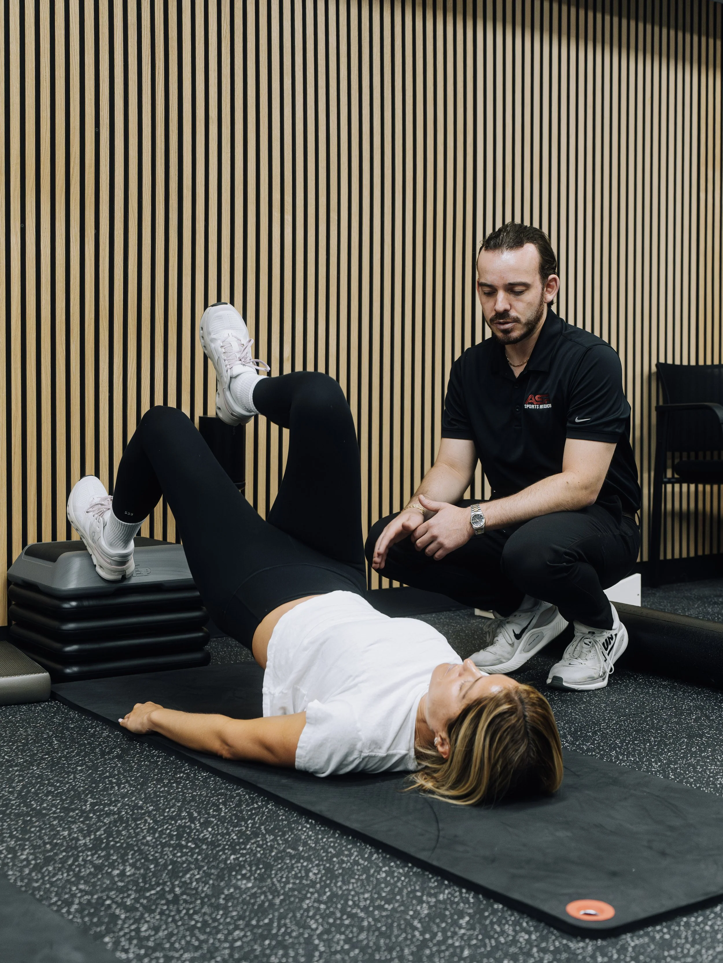 Physical therapist stretching a patient's leg on a therapy table in a clinic.