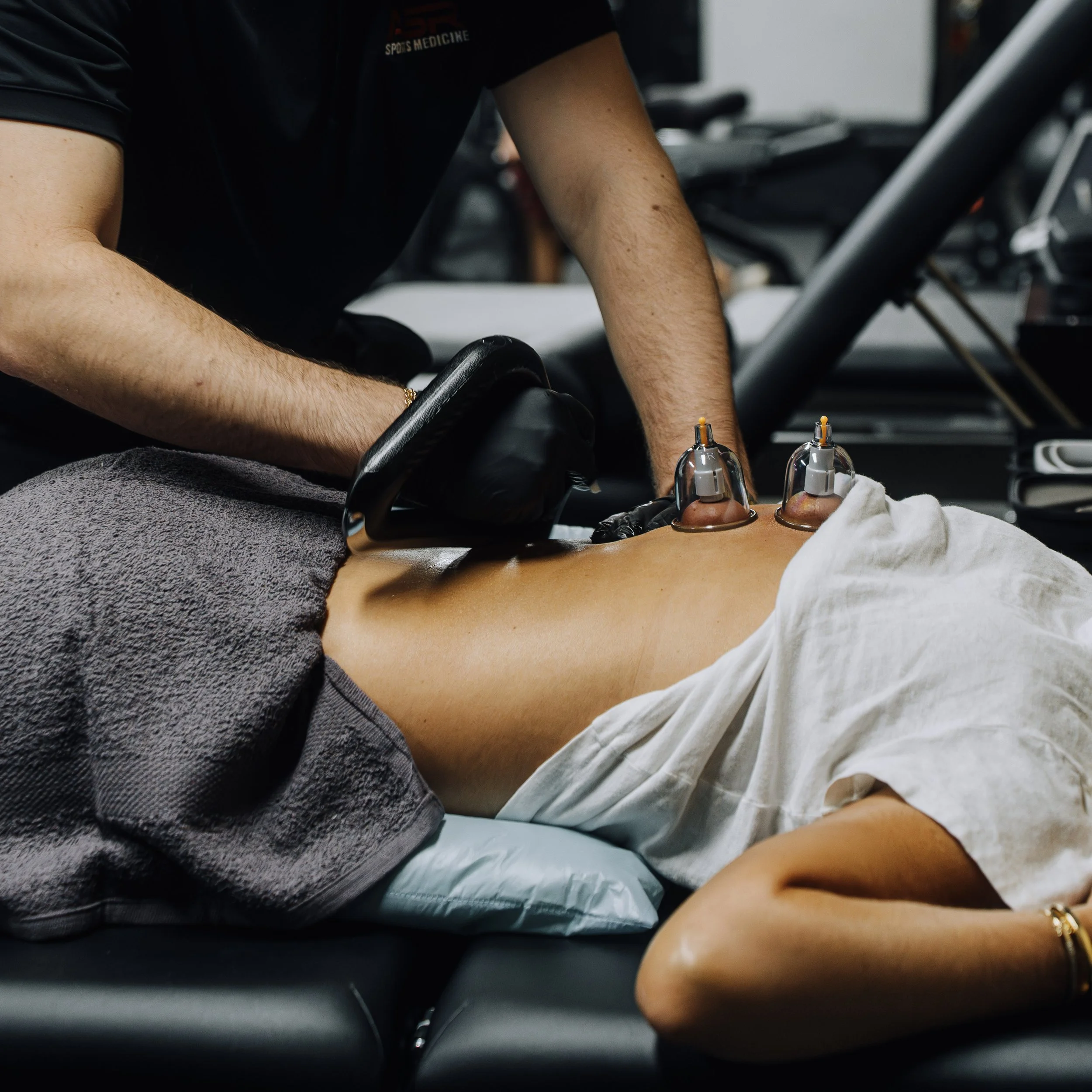A physical therapist performs back therapy on a man lying on a treatment table.