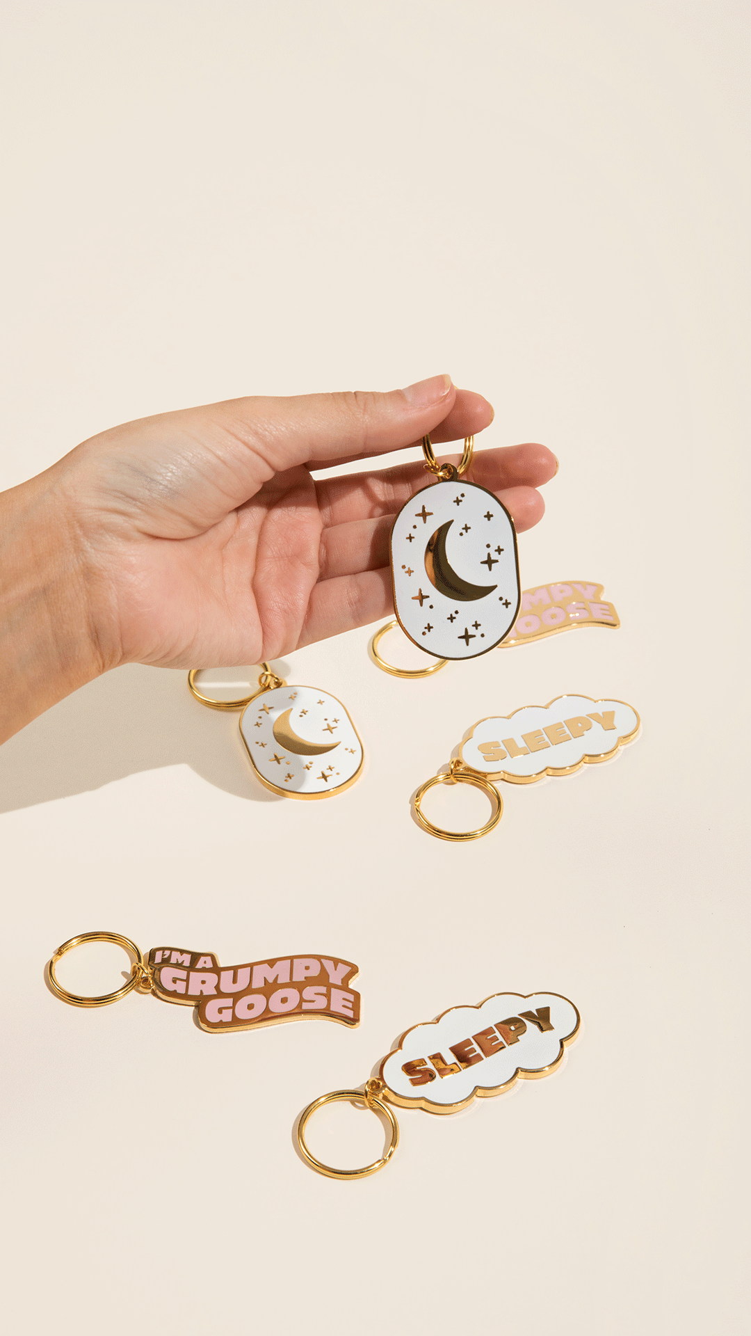 An oval, double-sided white keychain featuring a night sky with a crescent moon and twinkling stars.