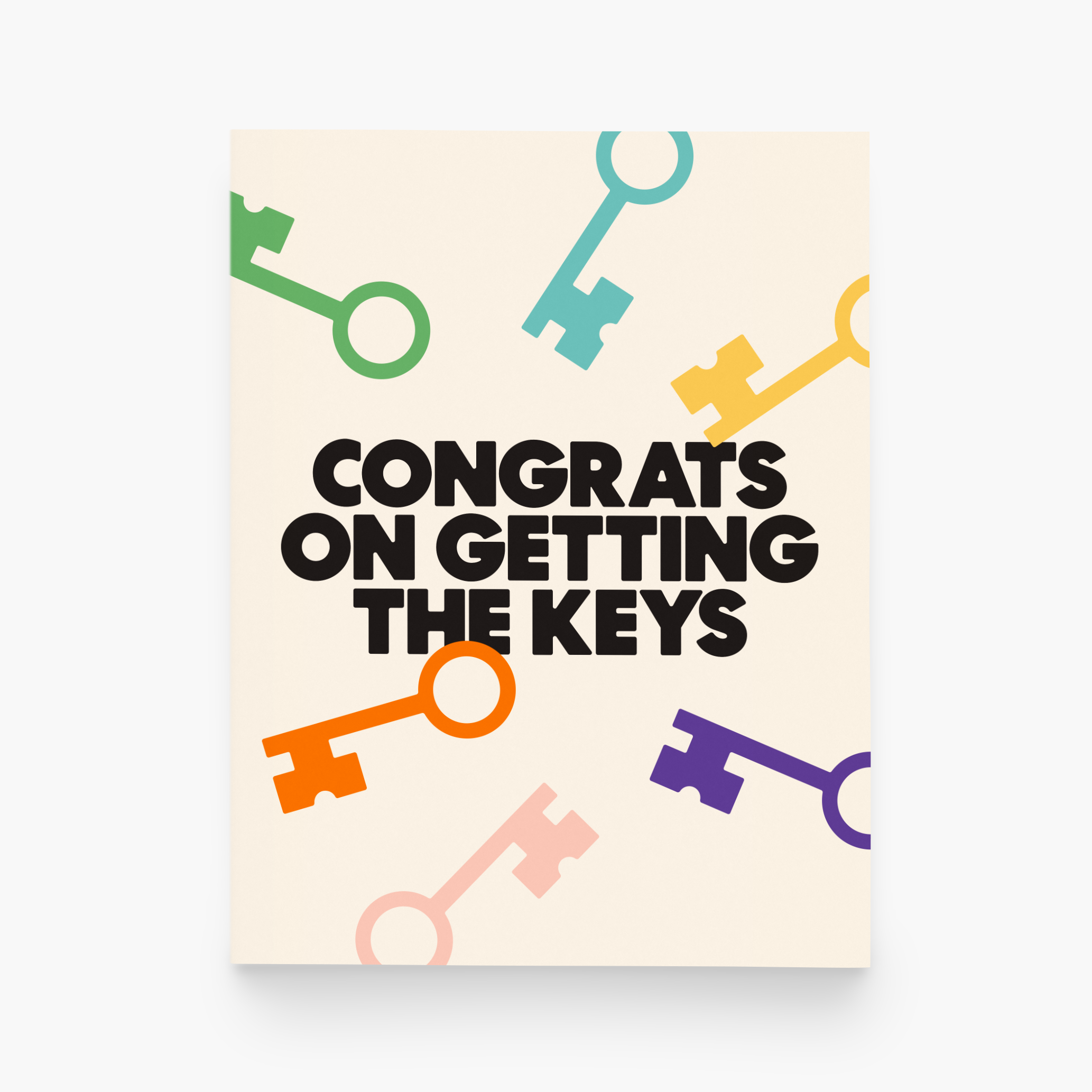 A creme greeting card says "congrats on getting the keys" in bold black text. Colorful keys surround the text in a circle.